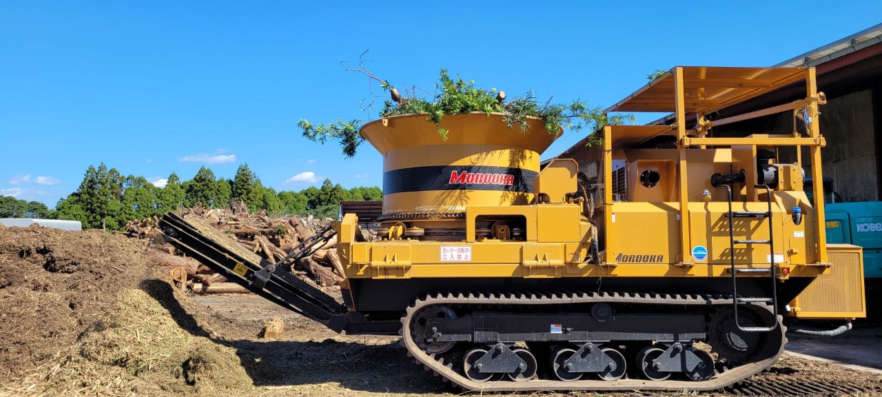 Grass, leaves, and wood are broken down through a machine. The material is then mixed with collected food waste to form compost.