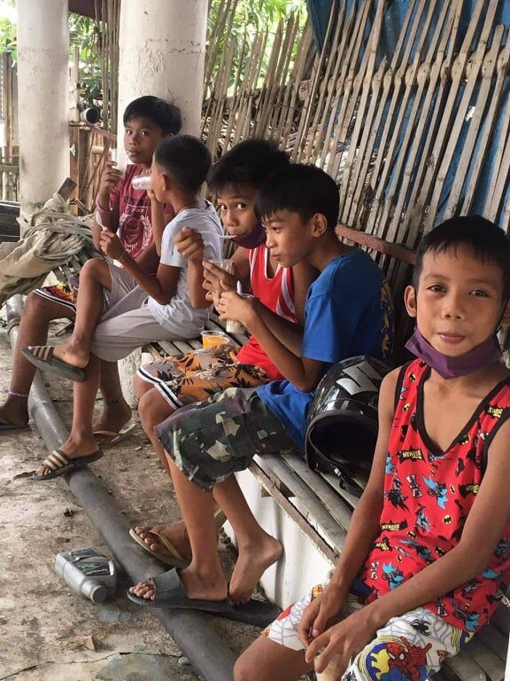 The children of Mina, Iloilo in the central Philippines enjoy soup while waiting for their turn to get a free haircut.