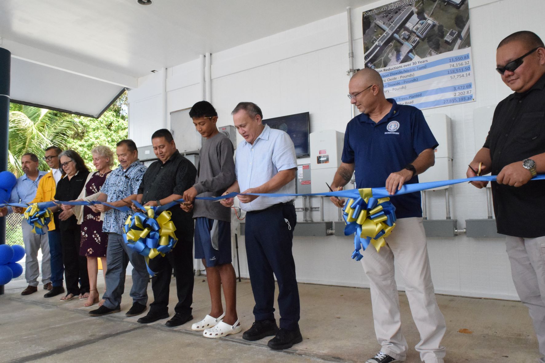Gov. Ralph DLG Torres, fifth right, Education Commissioner Alfred Ada, fifth left, Board of Education Chairman Gregory Borja, second right, BOE Member Andrew Orsini, third right, other education officials, and Micronesia Renewable Energy Inc. Chief Operations Officer Jeffrey Voacolo, left,  cut the ceremonial ribbon to mark the activation of the solar energy system at Marianas High School on Wednesday.