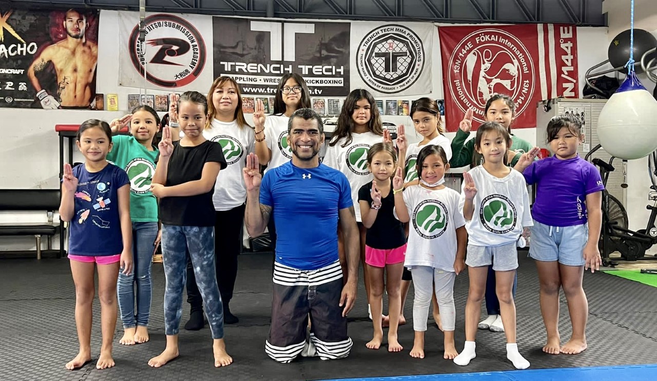The NMI Girl Scouts and MMA instructor Cuki Alvarez flash the Girl Scouts sign at Trench Tech Gym in Garapan on Saturday, Oct. 8, 2022.