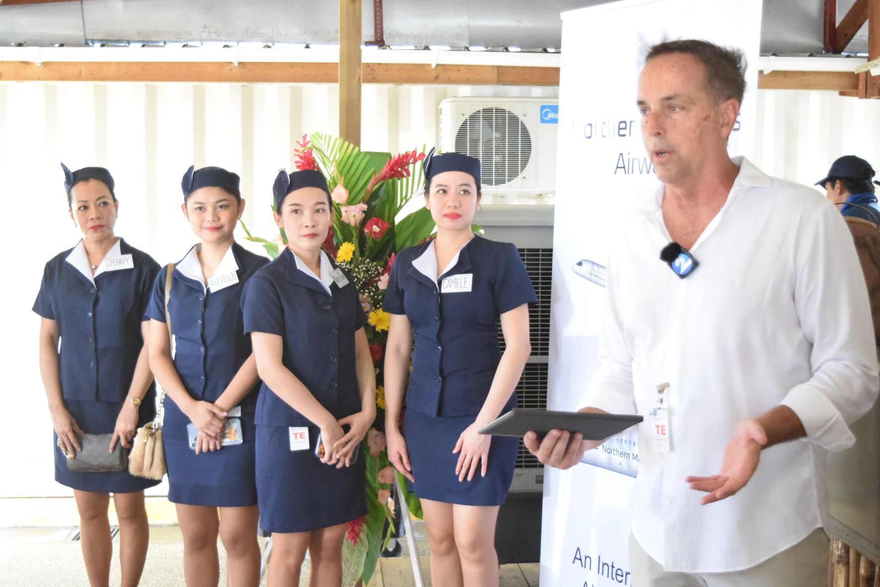 Northern Marianas Airways President Keith Stewart delivers his remarks as flight attendants look on.