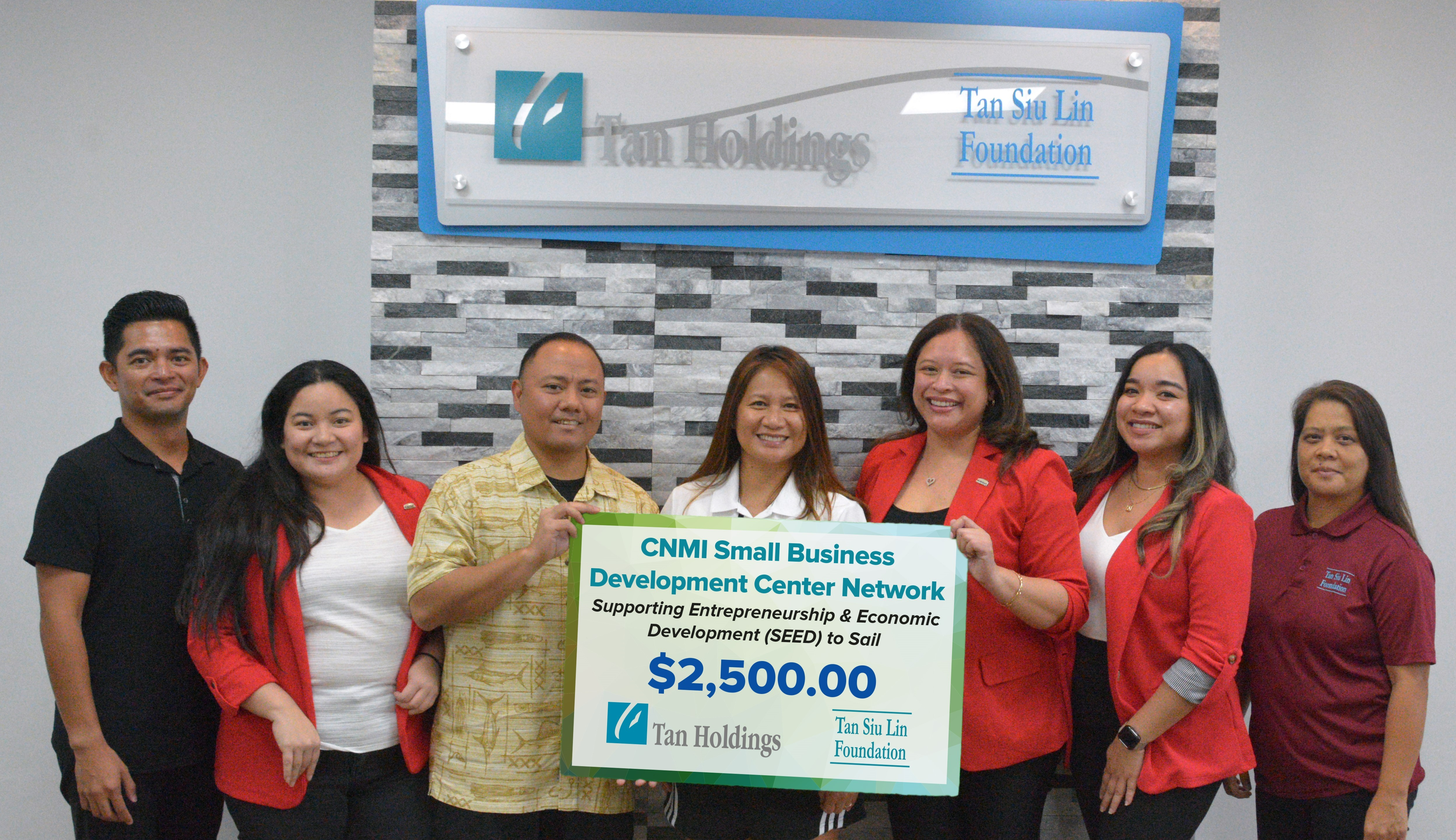Tan Siu Lin Foundation Executive Director Merlie Tolentino, center, presents the ceremonial check donation to CNMI Small Business Development Center Network representatives, led by its director, Nadine Deleon Guerrero, fifth left, during a turnover ceremony in the JP Center conference room early this month in support of the SEED to Sail Program.