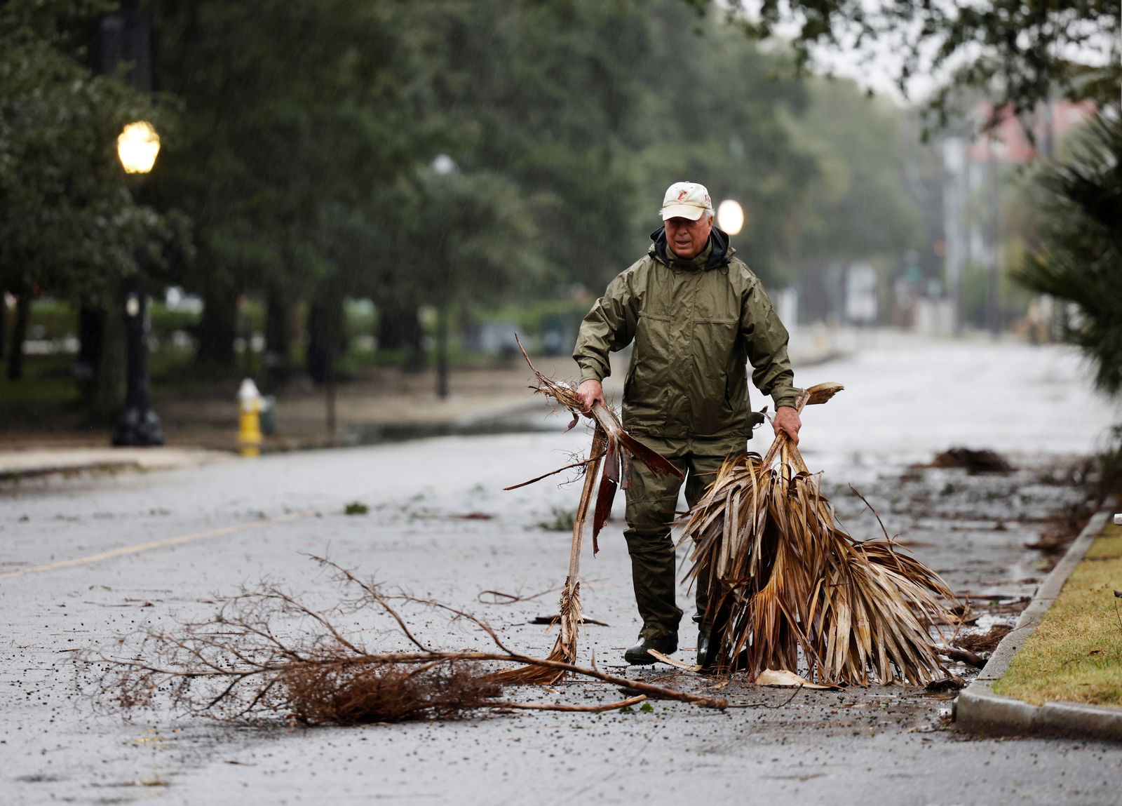 A local resident hauls debris from the road in an effort to keep gutter drains clear as hurricane Ian bears down on Charleston, South Carolina, Sept. 30, 2022.