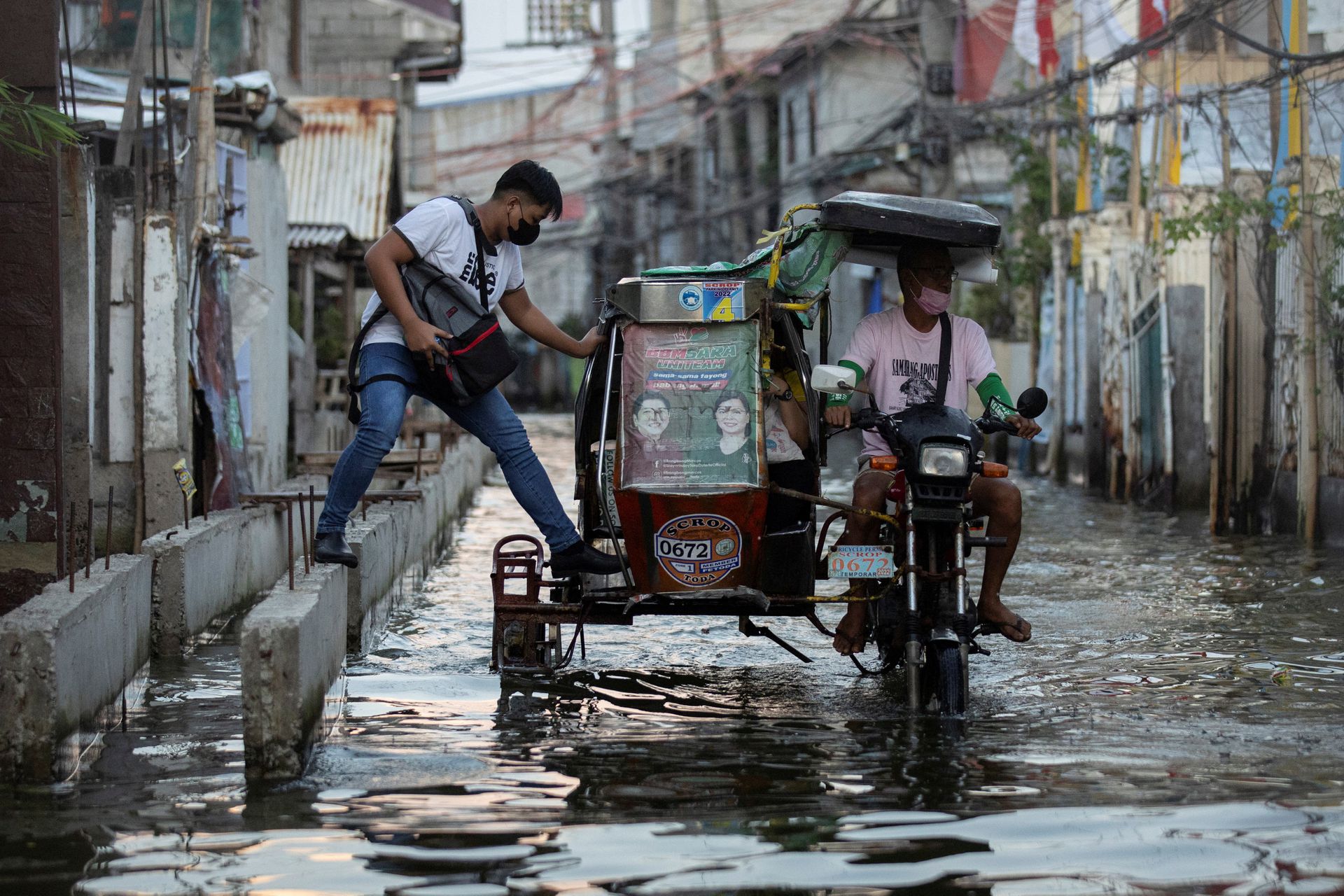 A man steps in a motorcycle taxi, modified to cope with flooding, in the coastal town of Hagonoy, Bulacan province, north of Manila, the Philippines, Sept. 23, 2022.