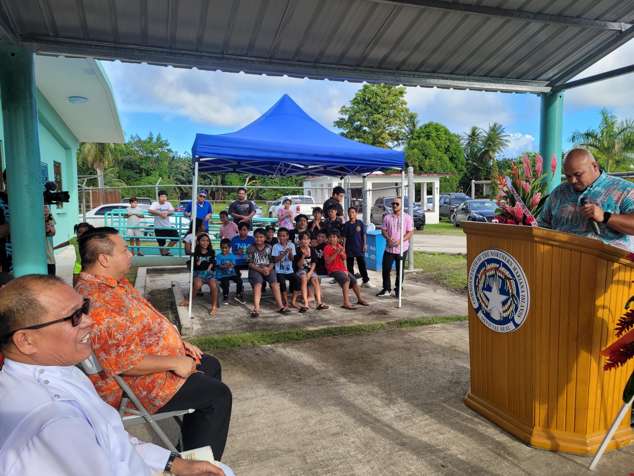 Special Assistant for Youth Affairs Office Ali Ogo, right, delivers his remarks during the reopening of the Chalan Kanoa Youth Center on Oct. 27, 2022. Also in the photo are Gov. Ralph DLG Torres, Fr. Ray Rosal of the Mt. Carmel Cathedral Parish and young community members.