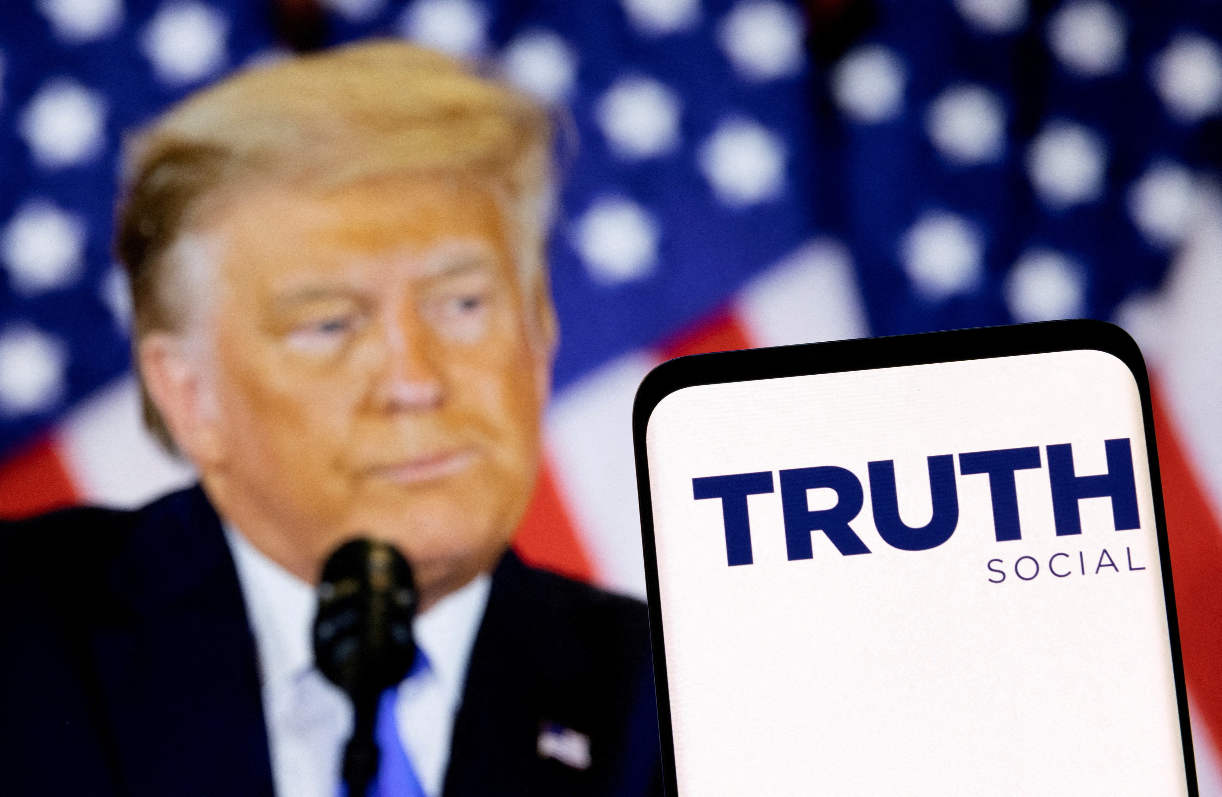 The Truth social network logo is seen on a smartphone in front of a display of former President Donald Trump in this picture illustration taken on Feb. 21, 2022.