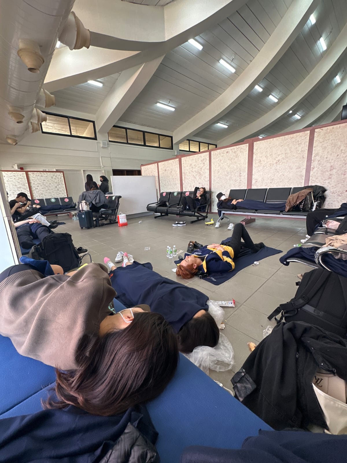 K-Pop performers and crewmembers rest at the Francisco C. Ada/Saipan International Airport while waiting for their flight back to South Korea.