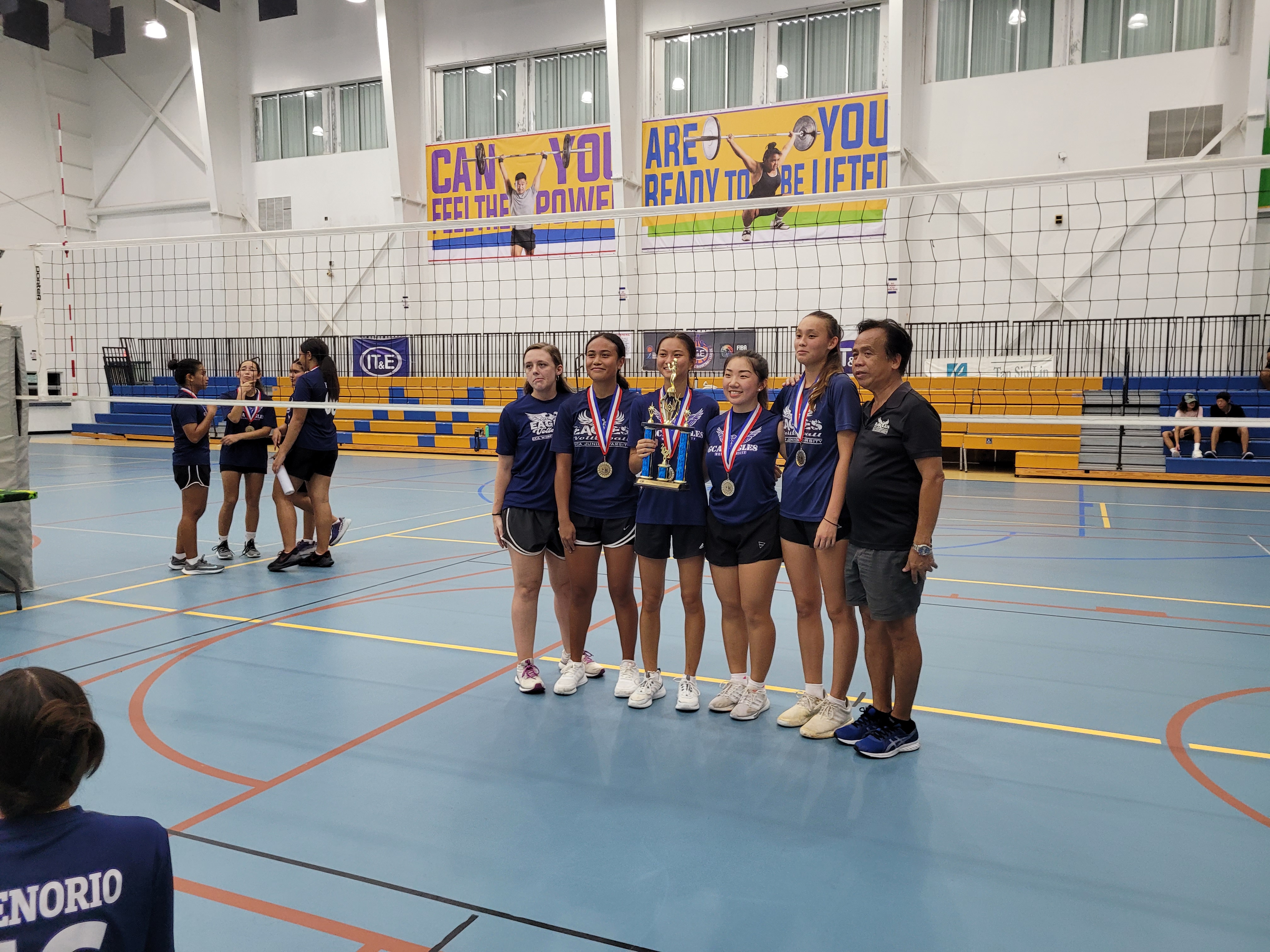 GCA seniors Katriel Saures, Soleil Lamar, Vicky Wa  and Hye Jin Elliott pose with their coach Cesar Libut and a schoolmate after winning their sixth consecutive NMIVA-PSS Girls High School Volleyball title at the MHS gym on Saturday.