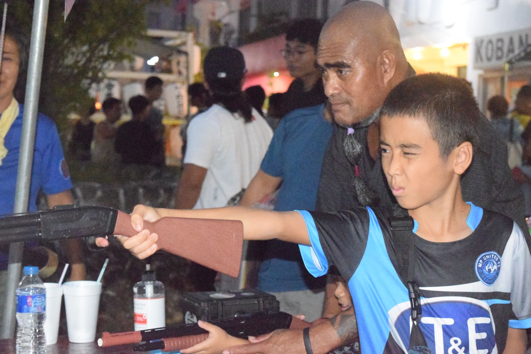 A boy aims at a target as his father looks on at one of the fun booths during the Japanese Autumn Festival at the Paseo De Marianas on Saturday.