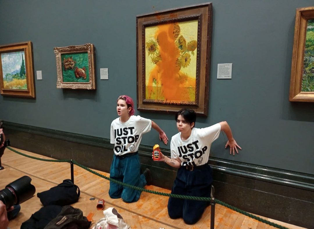 Activists of "Just Stop Oil" glue their hands to the wall after throwing soup at a van Gogh's painting "Sunflowers" at the National Gallery in London, Britain, October 14, 2022.