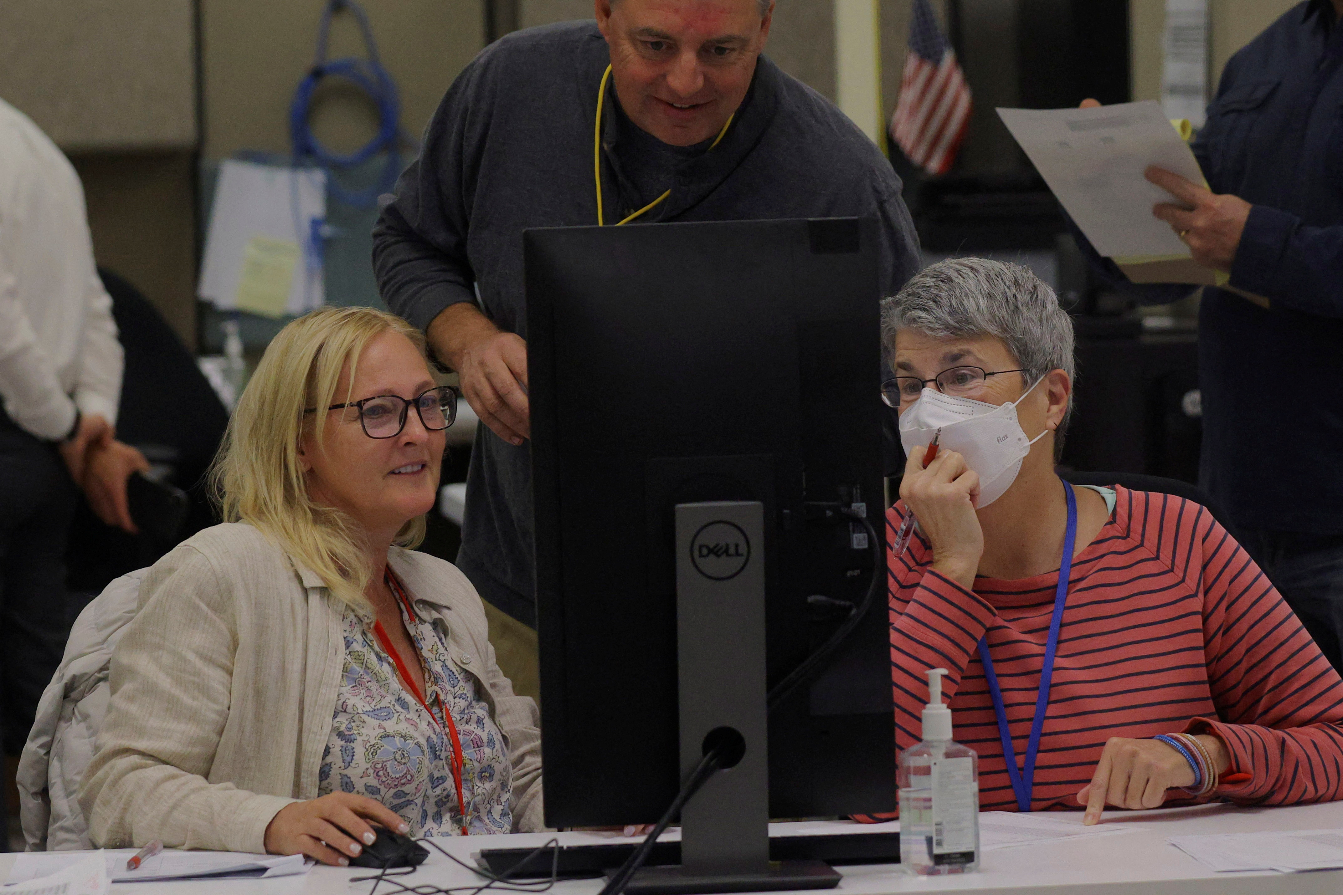 A neutral worker and  Republican and Democratic representatives adjudicate ballots cast in the midterm elections at the Maricopa County Tabulation and Election Center in Phoenix, Arizona,  Nov. 9, 2022.