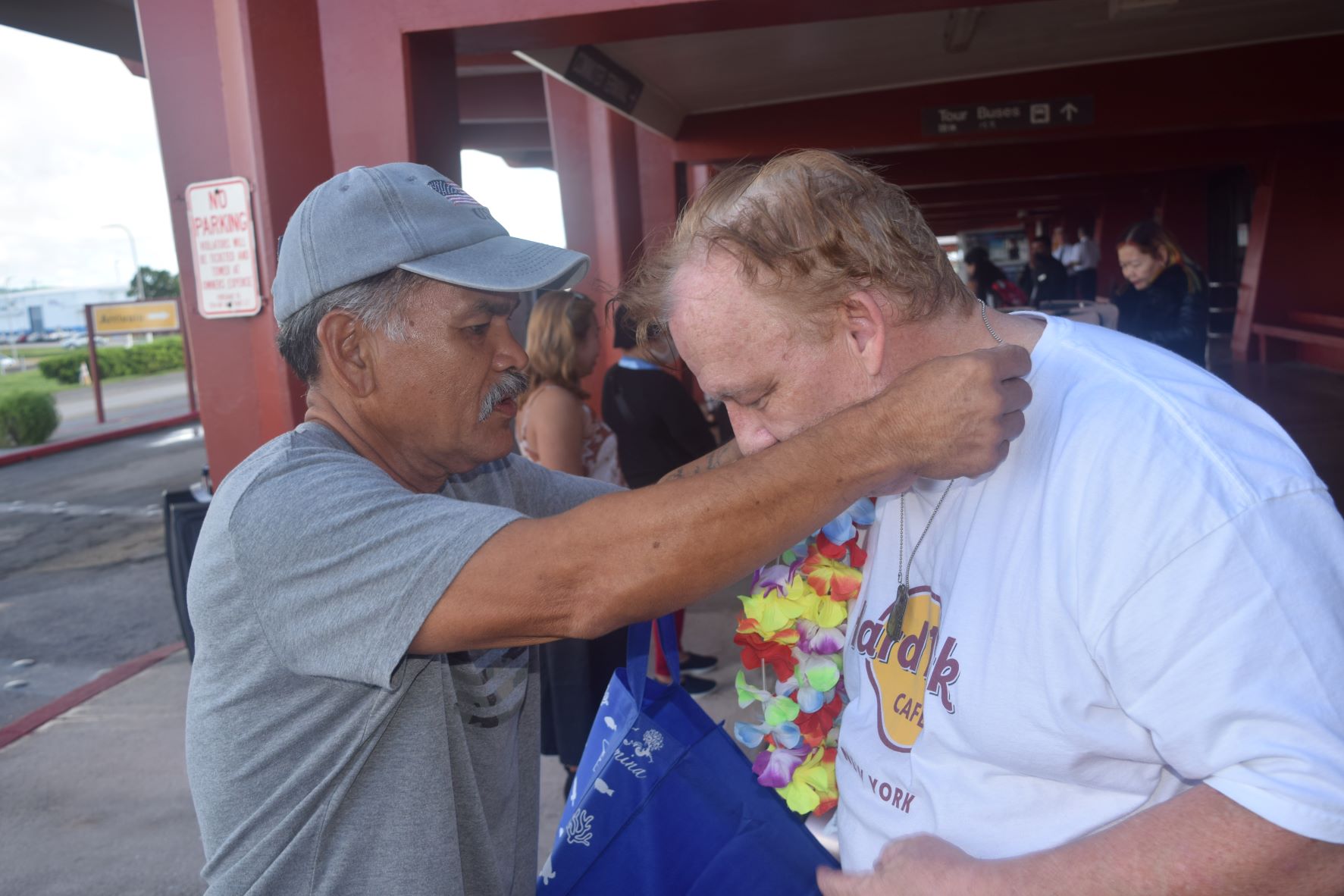 Military veteran Fabian Indalecio puts a dog tag on Jack Deeds, the son of an American soldier who saw action on Saipan in 1944.