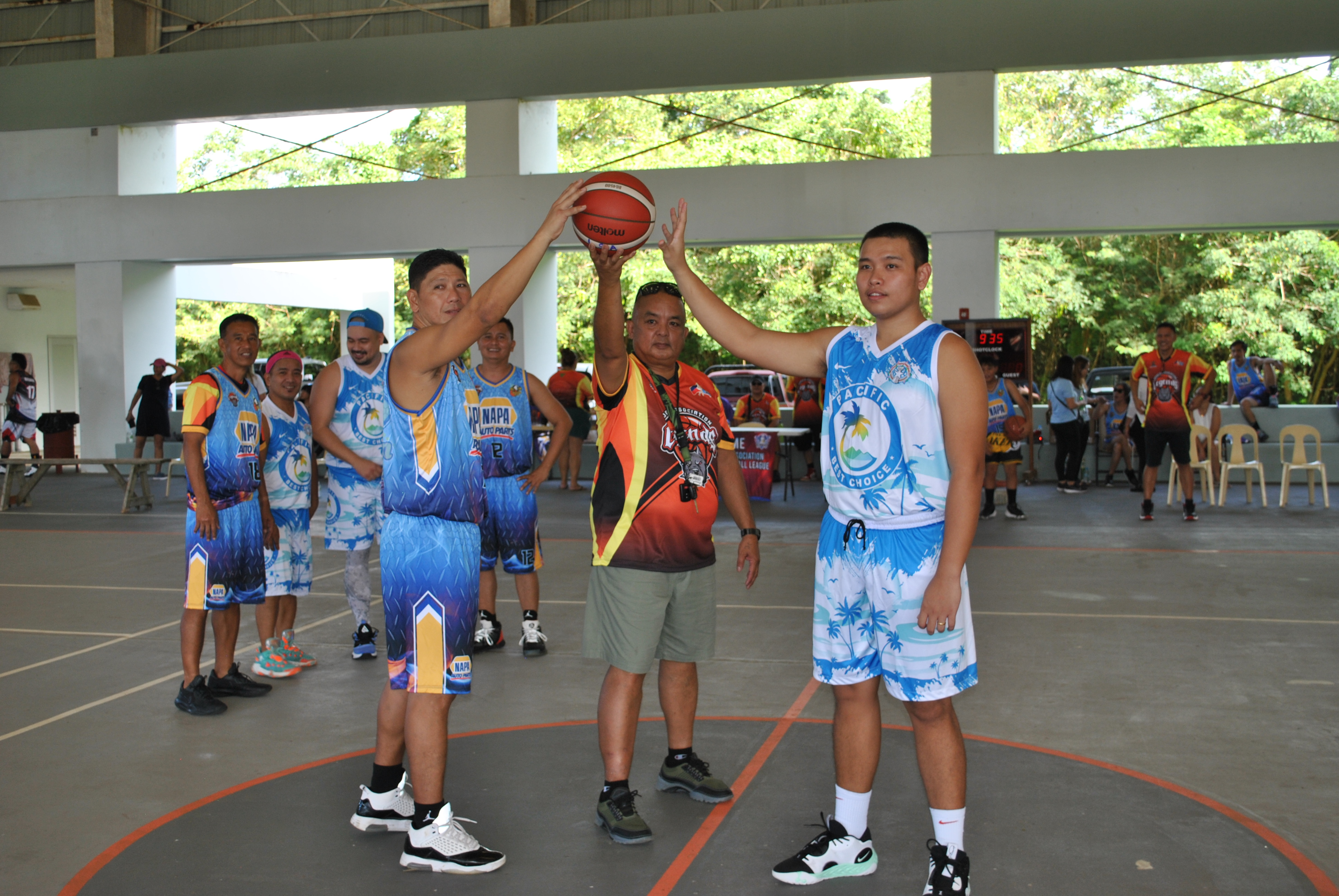 Pacific Best Choice and Napa players, along with John Dela Cruz, pose for a photo prior to the center toss during the opening ceremony of the Legends Sports Association Invitational Basketball League Sunday at Koblerville gym.