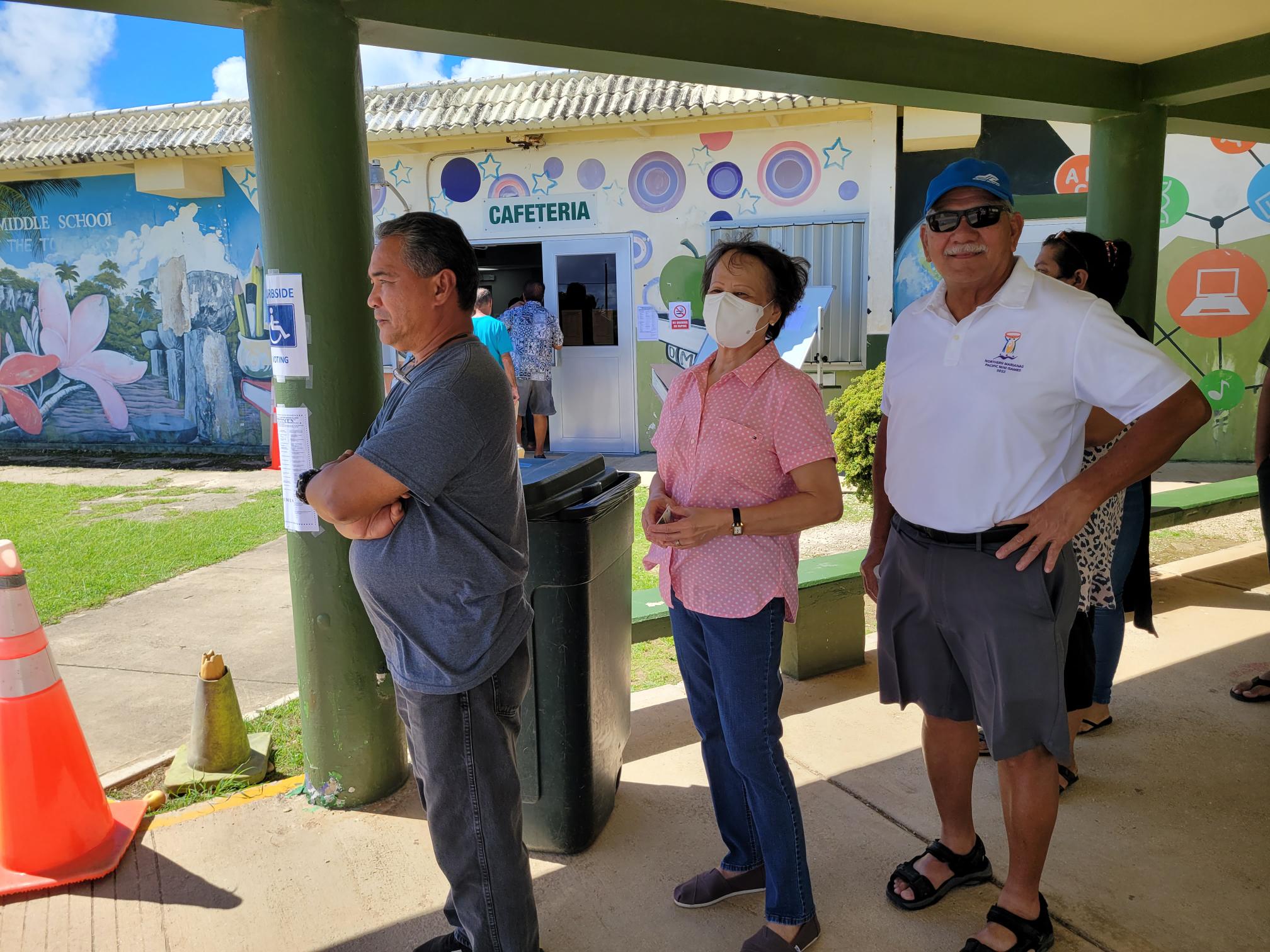Attorney General Edward Manibusan, right, lines up to cast his vote on Tuesday at Dandan Middle School.