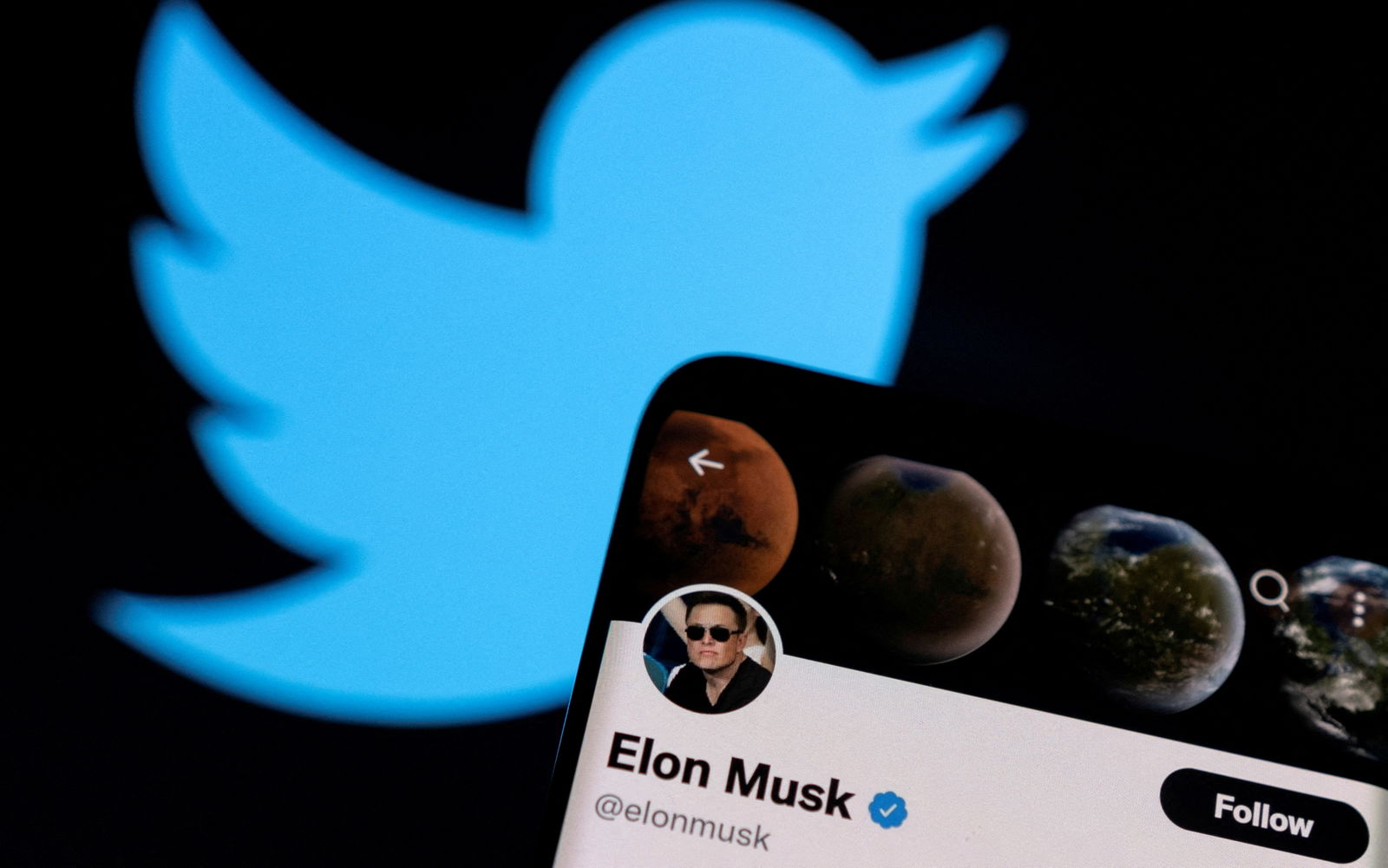Elon Musk's Twitter account is seen on a smartphone in front of the Twitter logo in this photo illustration taken, April 15, 2022.
