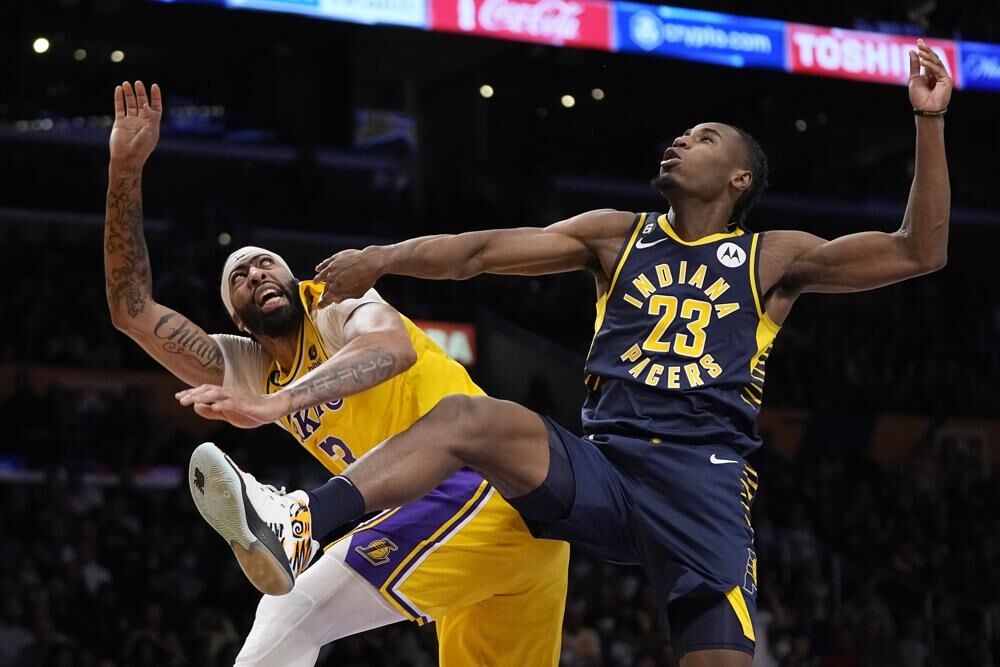 Los Angeles Lakers forward Anthony Davis, left, shoots as Indiana Pacers forward Aaron Nesmith defends during the first half of an NBA basketball game Monday, Nov. 28, 2022, in Los Angeles.