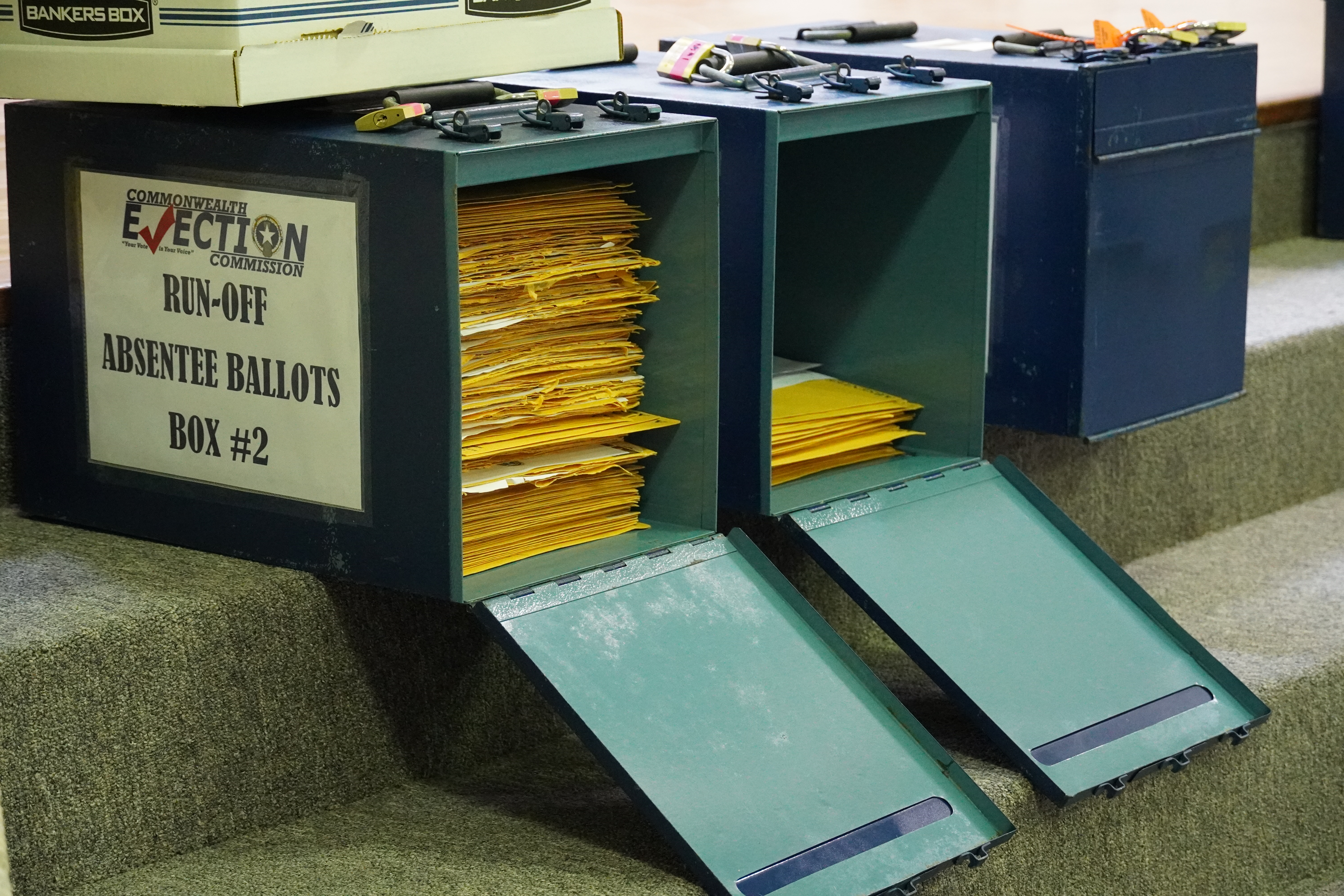 Runoff absentee ballot boxes — unlocked — await processing