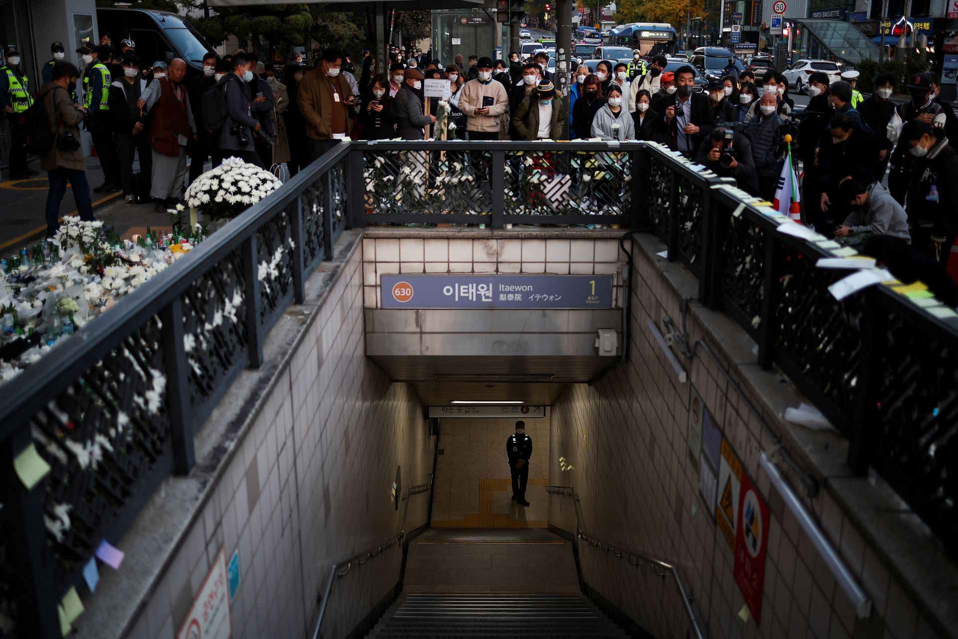 A police officer stands guard at the exit of a subway station as people gather to pay their respects following a crowd crush that happened during Halloween festivities, in Seoul, South Korea, Nov. 1, 2022.