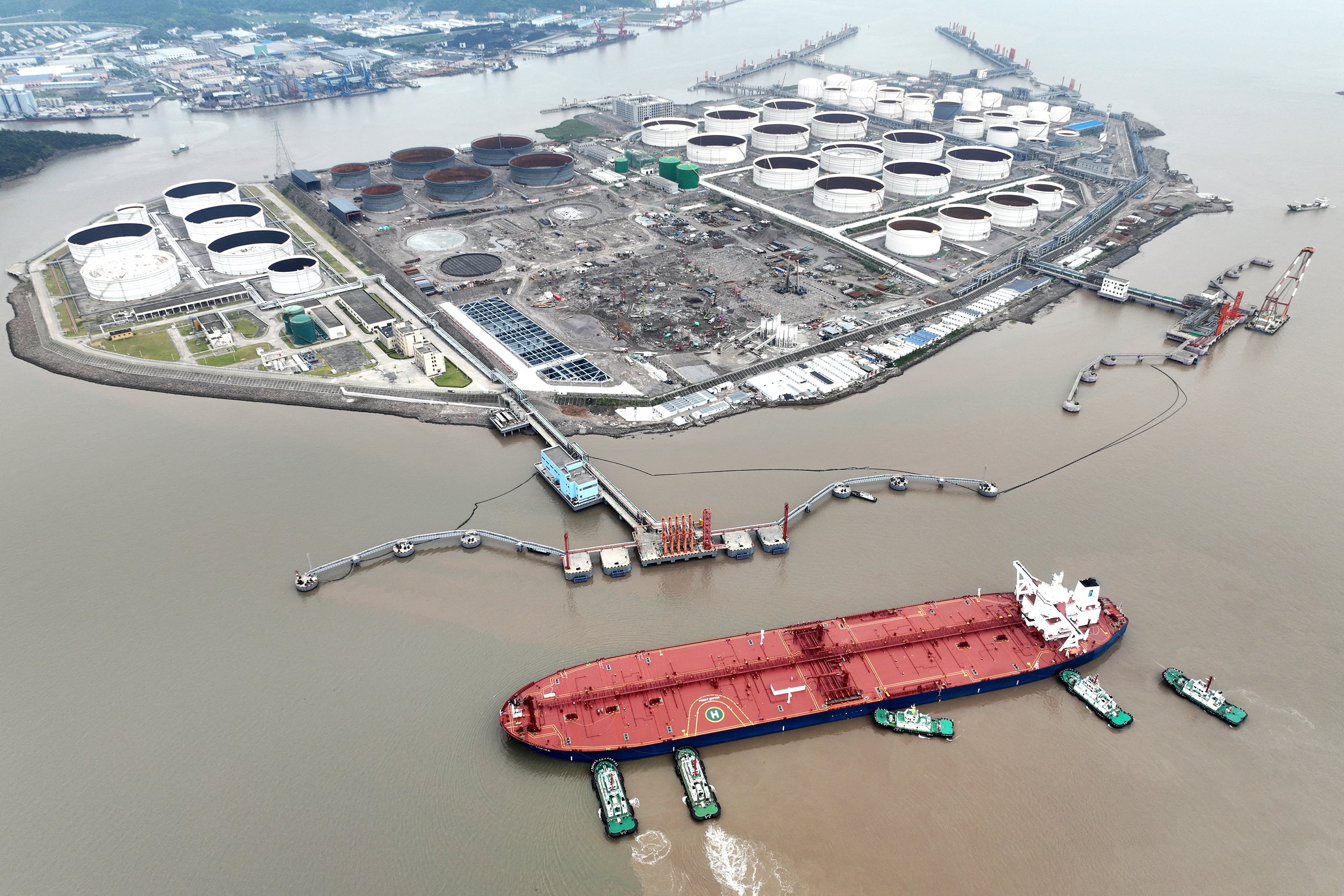 An aerial view shows tugboats helping a crude oil tanker to berth at an oil terminal, off Waidiao Island in Zhoushan, Zhejiang province, China on July 18, 2022.