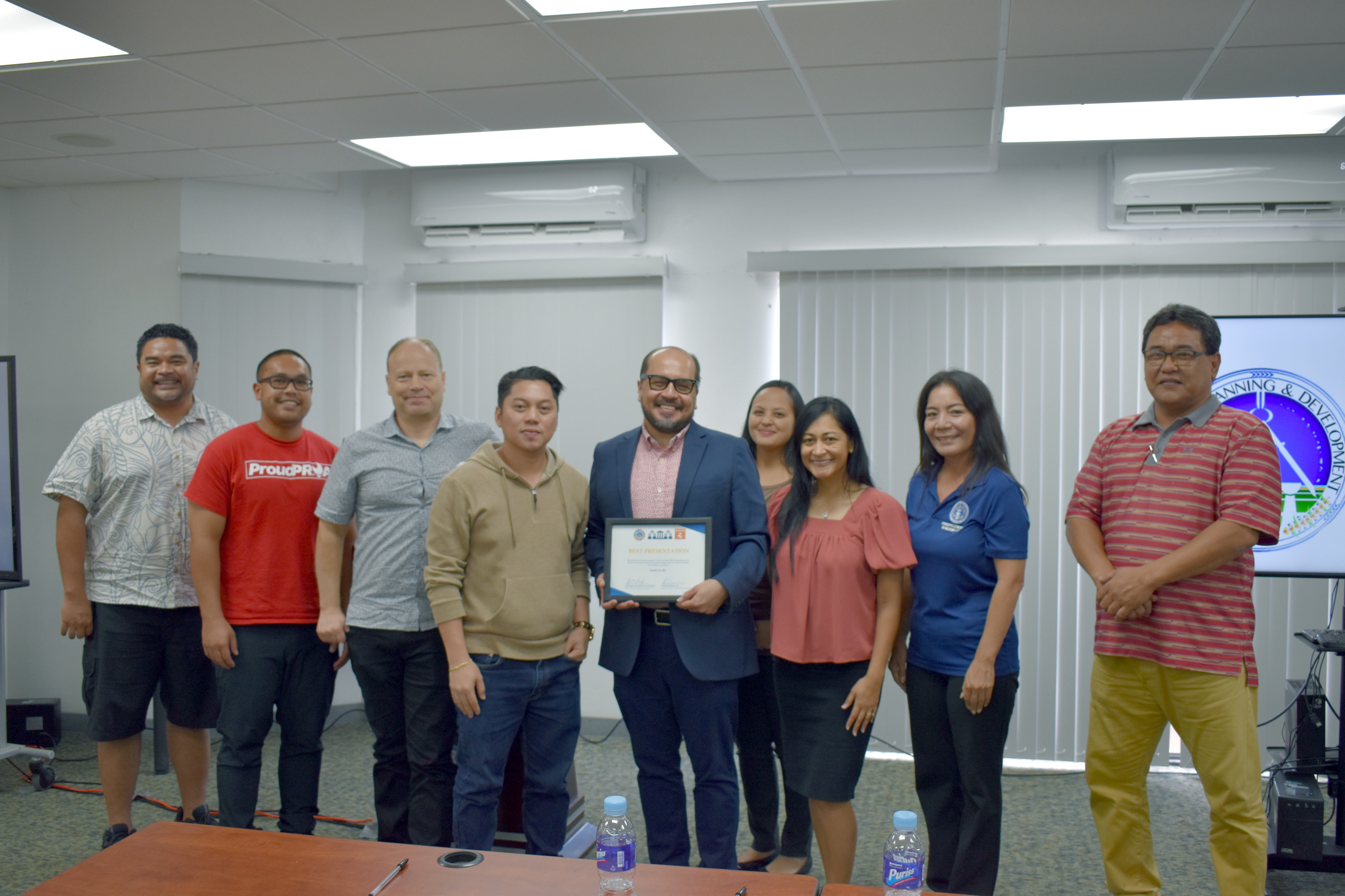 Northern Marianas College President Dr. Galvin Deleon Guerrero, fifth from left, holds up NMC’s “Best Presentation” award after the Community Pillars Awards Committee Presentations event held on Oct. 29 at the Commonwealth Utilities Corp. Conference Room. NMC’s proposed digital equity project is the “Proa Tech Café” which will serve as a social hub with high-speed internet and access to the college’s numerous educational, entrepreneurship, and workforce development resources. The café will be available to college students and the community alike.  Also included in the photo are Office of Planning and Development Director A. Kodep Ogumoro-Uludong, OPD Senior Policy Advisor on Broadband and Digital Equity Peter Dresslar, and Community Pillars Awards Committee members first lady Diann Torres, Glenna Sakisat Palacios, Nadia Benjamin, and Ray Lizama.