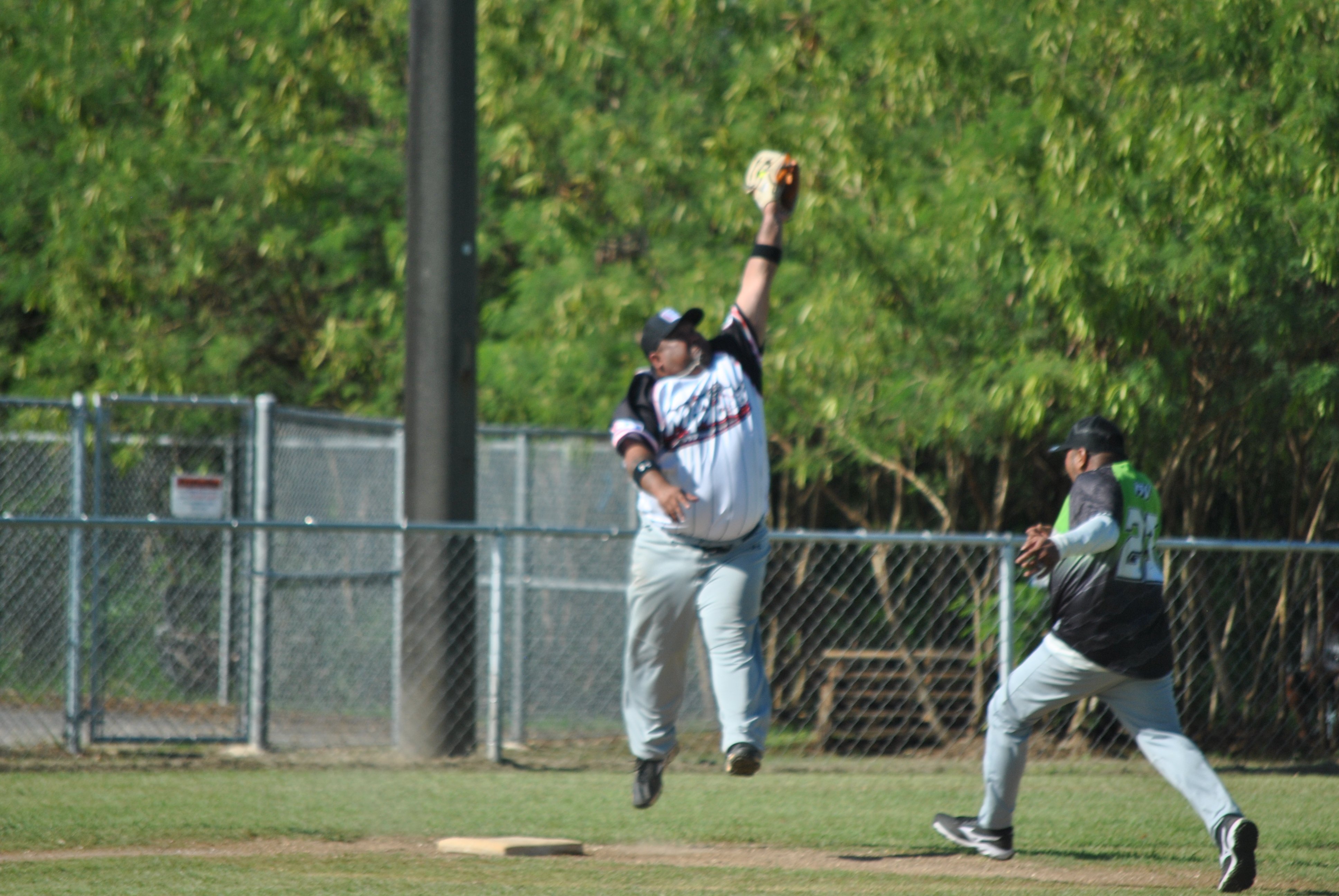 Man Amigos' Manny Sablan catches the ball in midair as Tokahao's George David rushes to reach third base safely during a Budweiser Belau Amateur Softball League game Sunday at the Dandan baseball field.