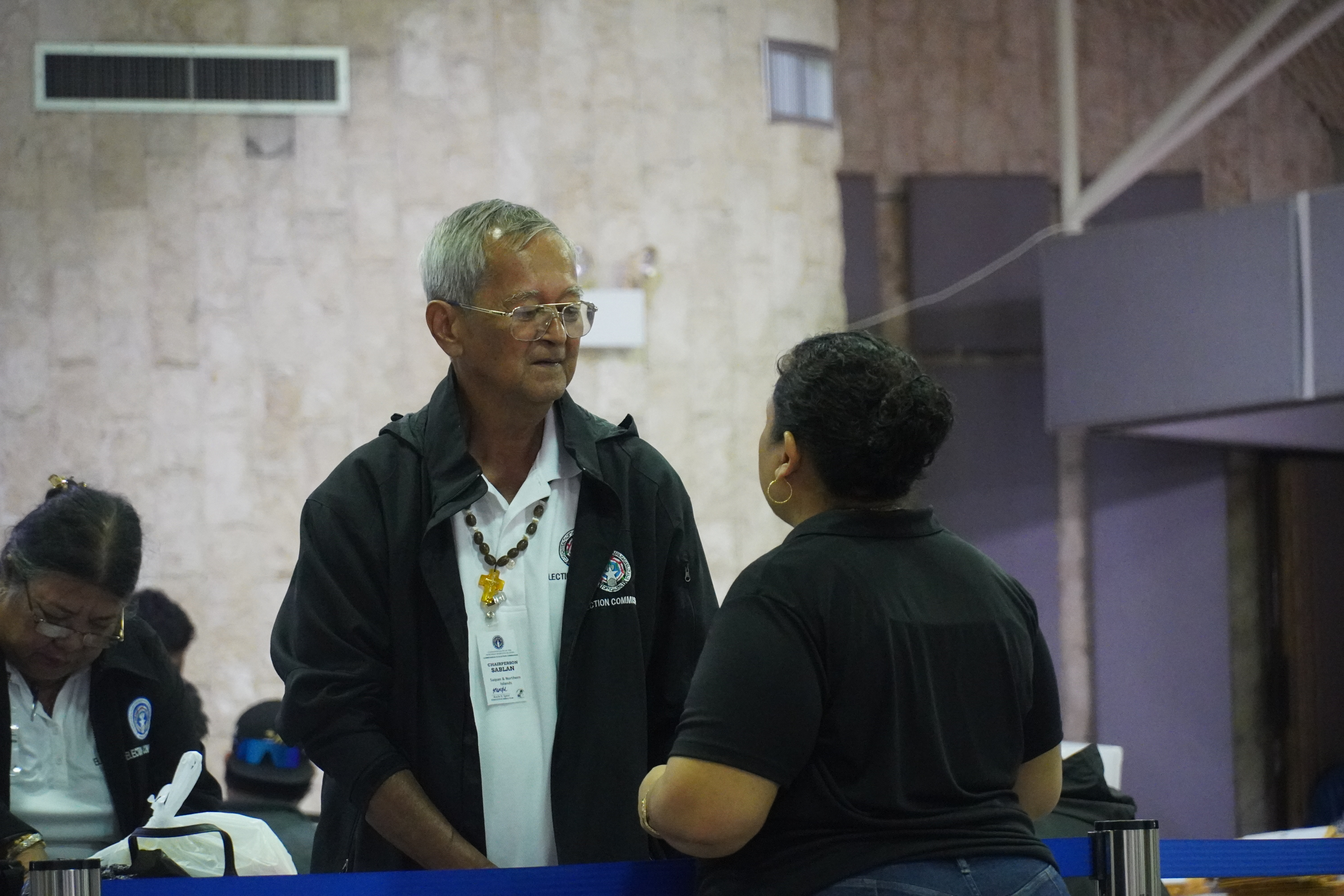 Commonwealth Election Commission Board Chair Jesus I. Sablan and Executive Director Kayla S. Igitol, back to the camera, converse prior to the tabulation of the ballots.