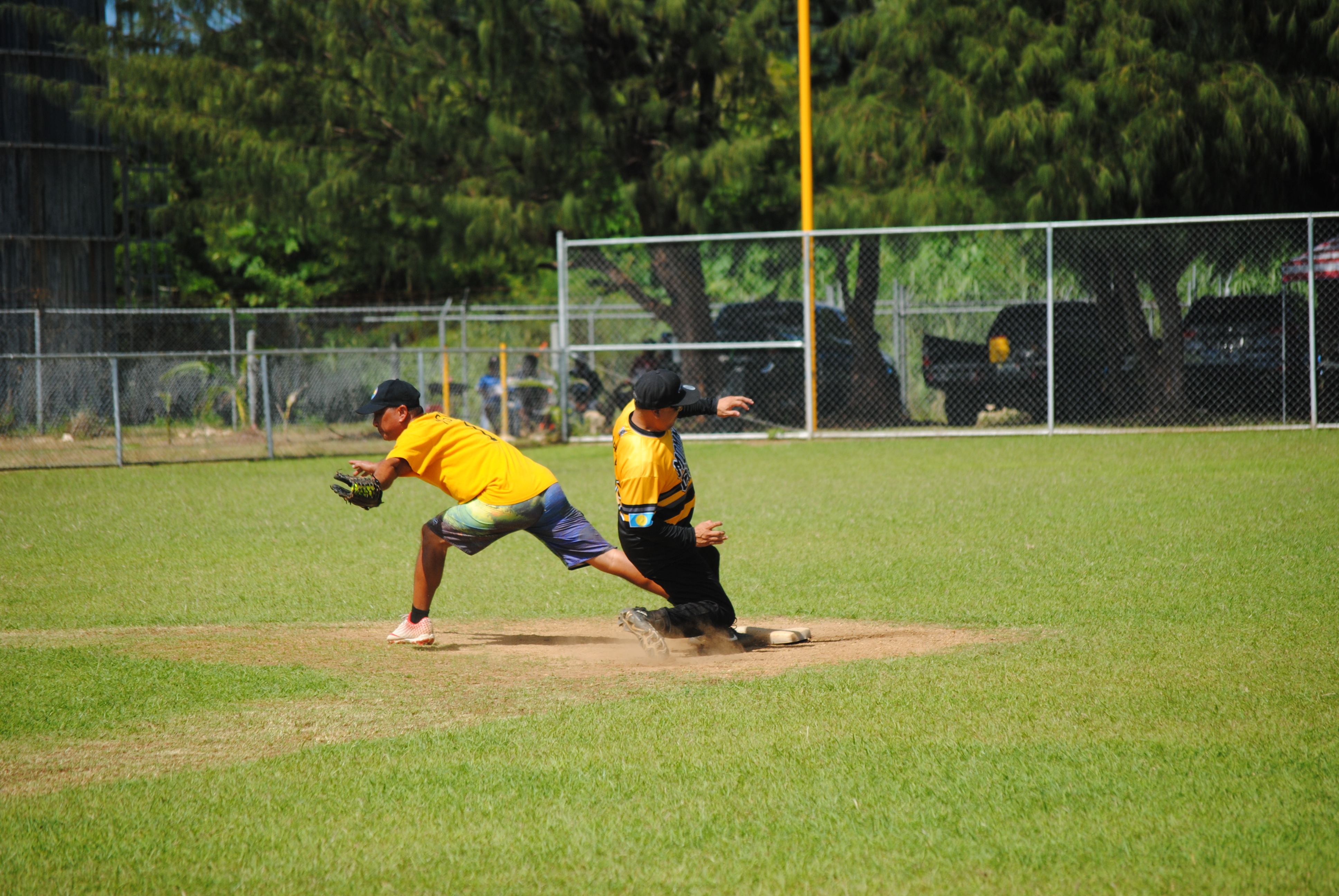 Momma Charu's Barney Maratita slides safely while Hagu Lamun second baseman Eric Tudela extends to catch the ball during a 2022 Budweiser Belau Amateur Softball League game Sunday at the Dandan baseball field.