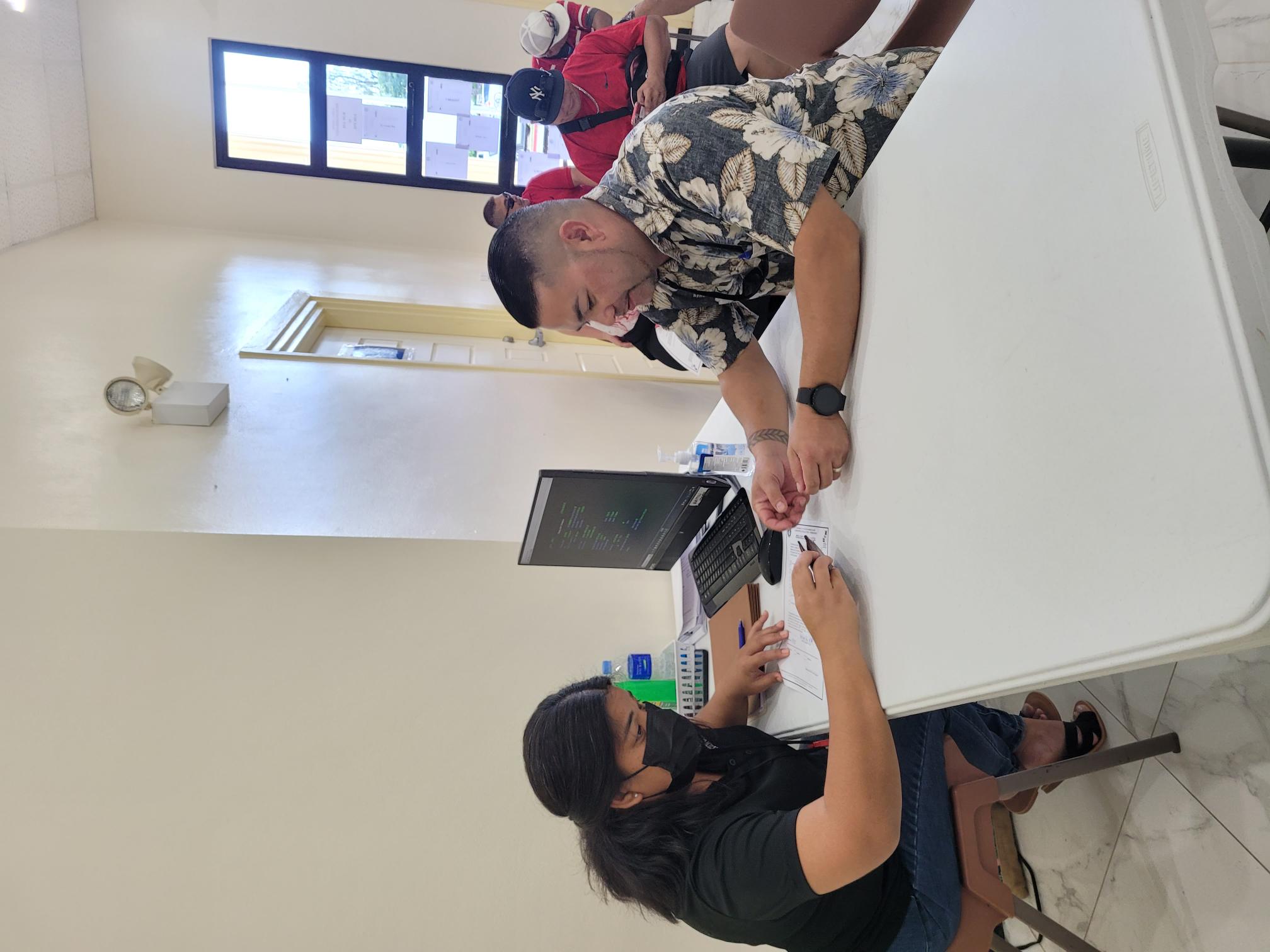 An election commission staff member reviews the early-voter form submitted by Senate Floor Leader Vinnie F. Sablan at the multi-purpose center Thursday.