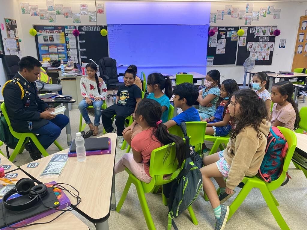 Kagman Elementary School students listen to a Kagman High School Ayuyu Battalion cadet read a book on Wednesday at KagES.