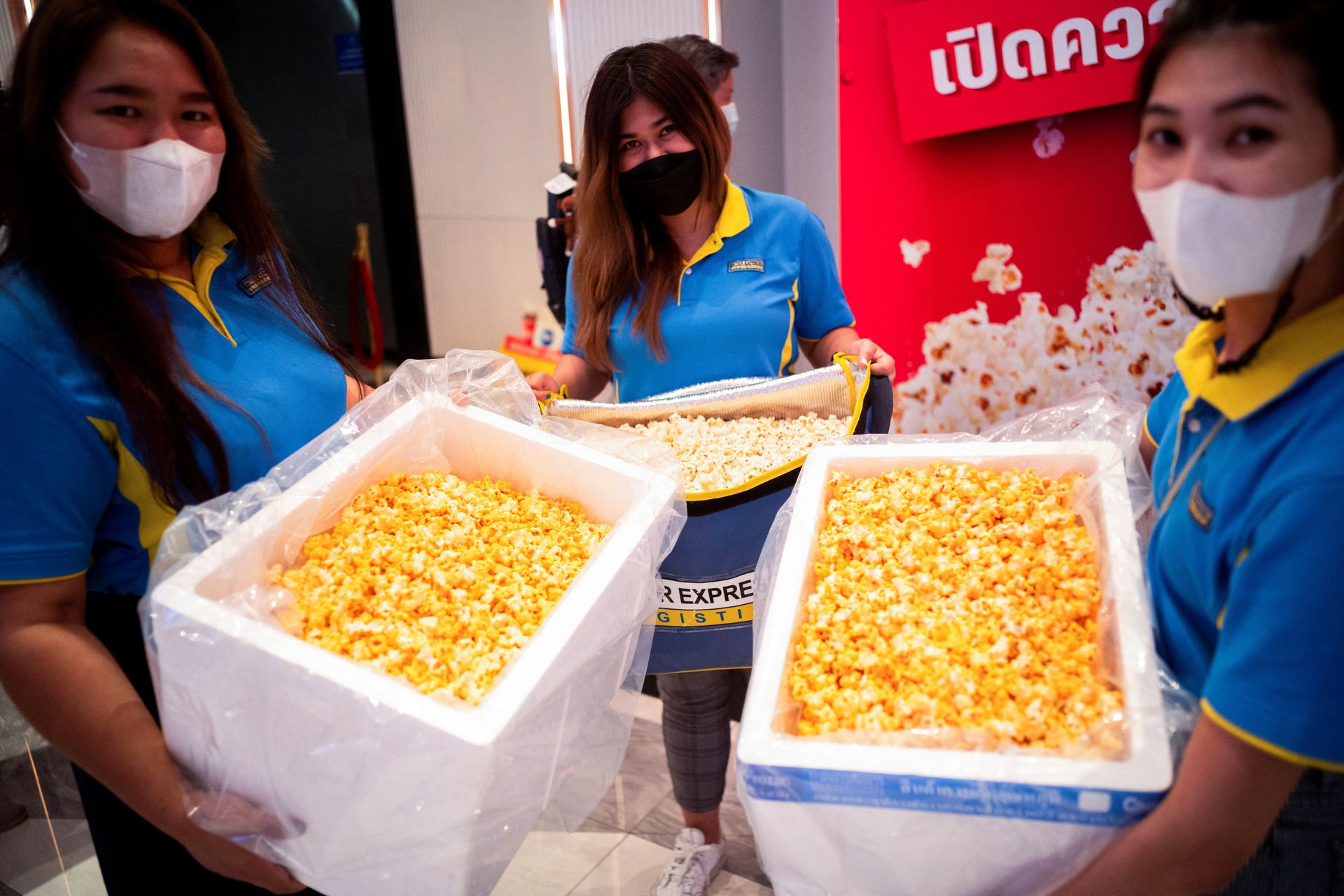 Women carrying foam boxes containing popcorn during an "all you can eat popcorn for 199 baht ($5.60)" promo in front of a cinema inside a department store in Bangkok, Thailand, Nov. 28, 2022.