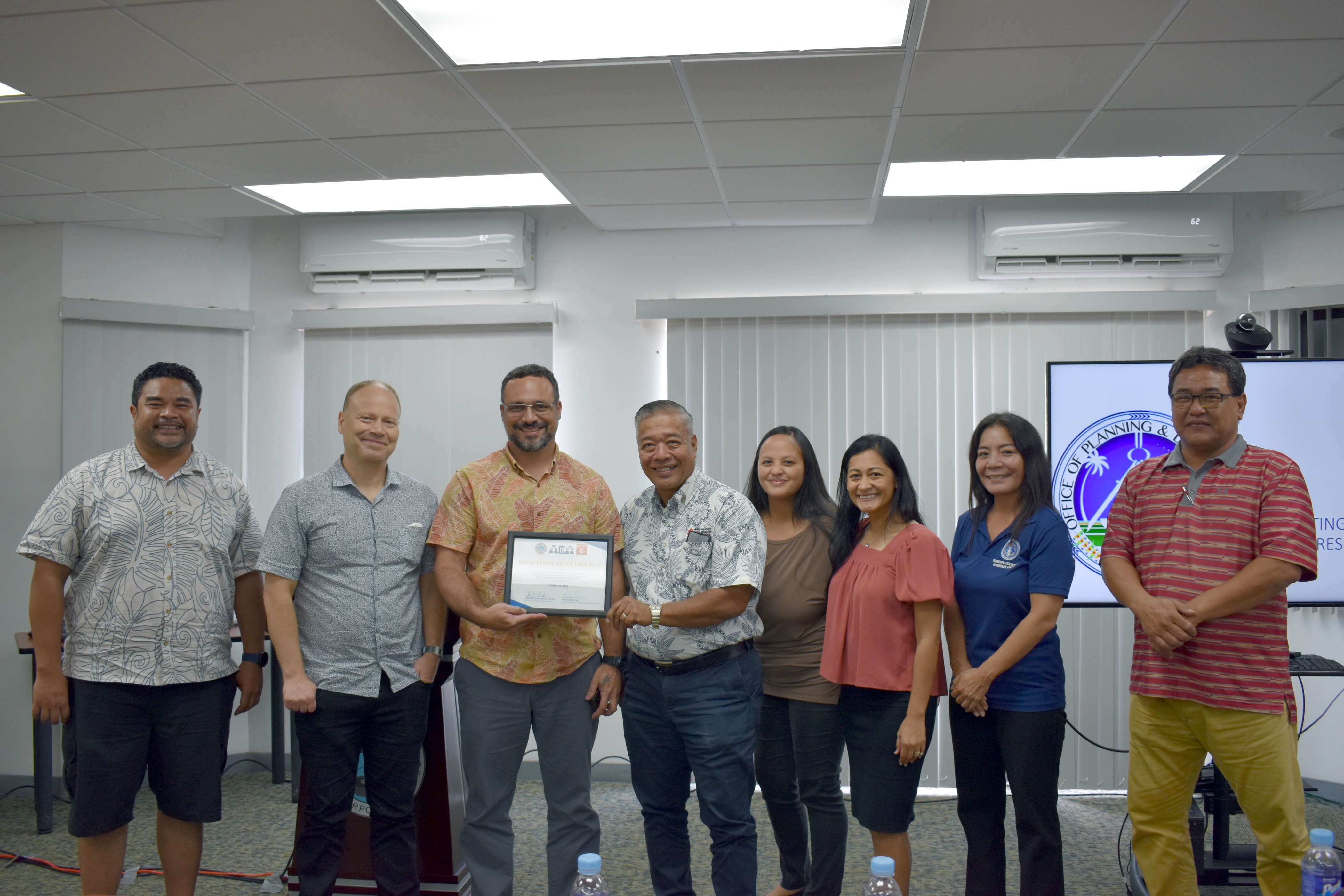 Northern Marianas Humanities Council Executive Director Leo Pangelinan and NMI Museum Director Daniel Aquino, third and fourth from left respectively, hold up the “Most Innovative Project” award after the Community Pillars Awards Committee Presentations event held on Oct. 29 at the Commonwealth Utilities Corp. Conference Room.  The Humanities Council’s proposed project, the Commonwealth Center for the Humanities, will provide the community a way to collect, exhibit, and transmit information about everyone’s humanity through both physical and virtual spaces.  Also included in the photo are Office of Planning and Development Director A. Kodep Ogumoro-Uludong, OPD Senior Policy Advisor on Broadband and Digital Equity Peter Dresslar, and Community Pillars Awards Committee members first lady Diann Torres, Glenna Sakisat Palacios, Nadia Benjamin, and Ray Lizama.