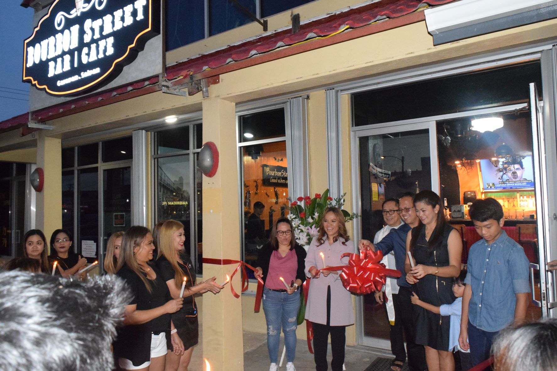 Eden Guillo Ordas, center, and co-owners Butch and Ailene Ordas, third and second right, celebrate with Father Chaui Borja, employees and guests after cutting the ribbon to open Bourbon Street Bar & Café in central Garapan on Friday.