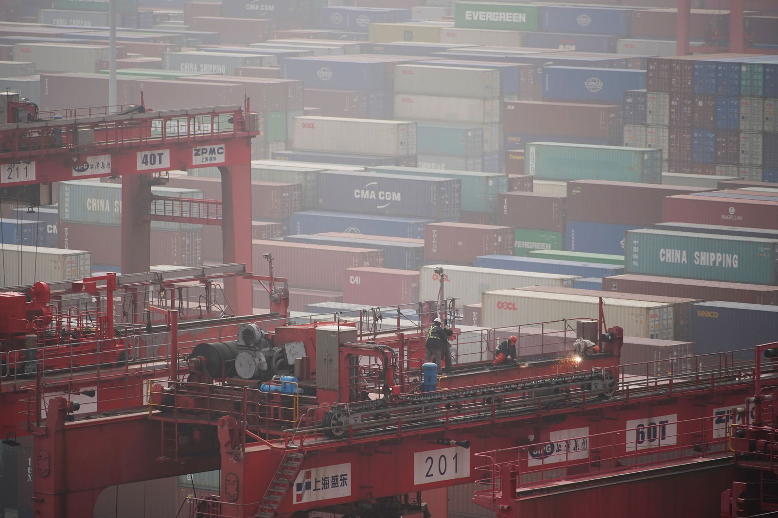 Workers are seen on a crane above containers at the Yangshan Deep Water Port in Shanghai, China on Jan. 13, 2022.