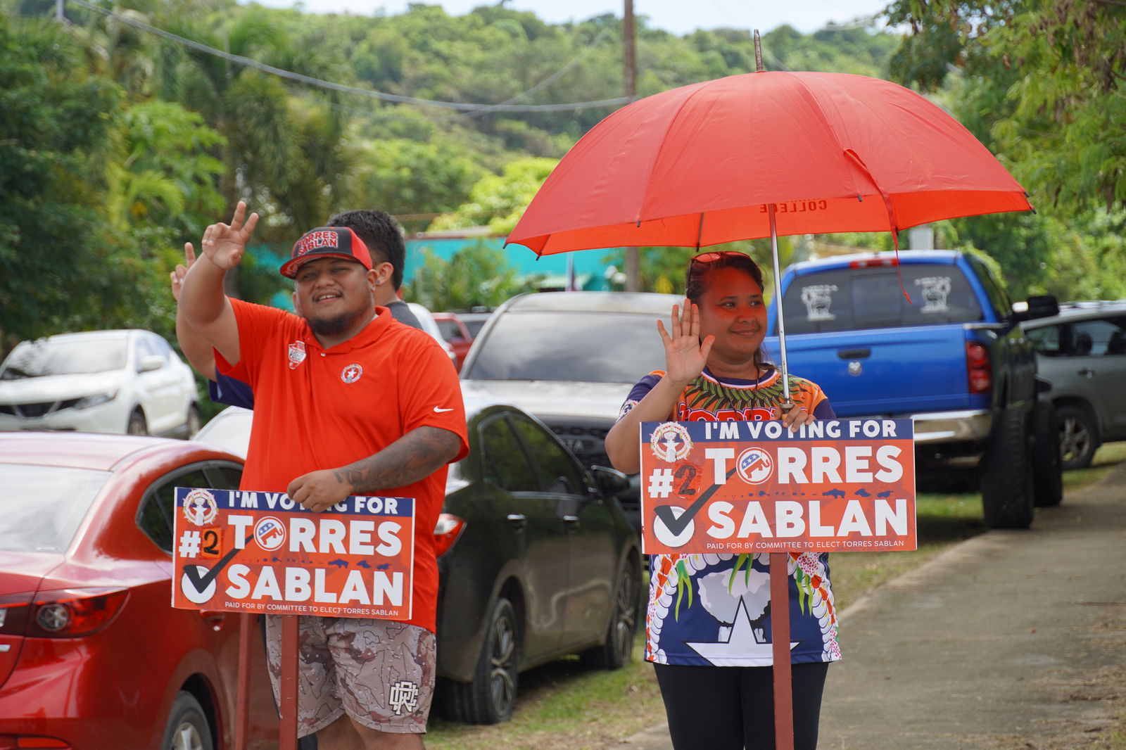 Precinct 5 Rep.-elect Thomas John DLC Manglona and another GOP supporter wave at passersby in Kagman.