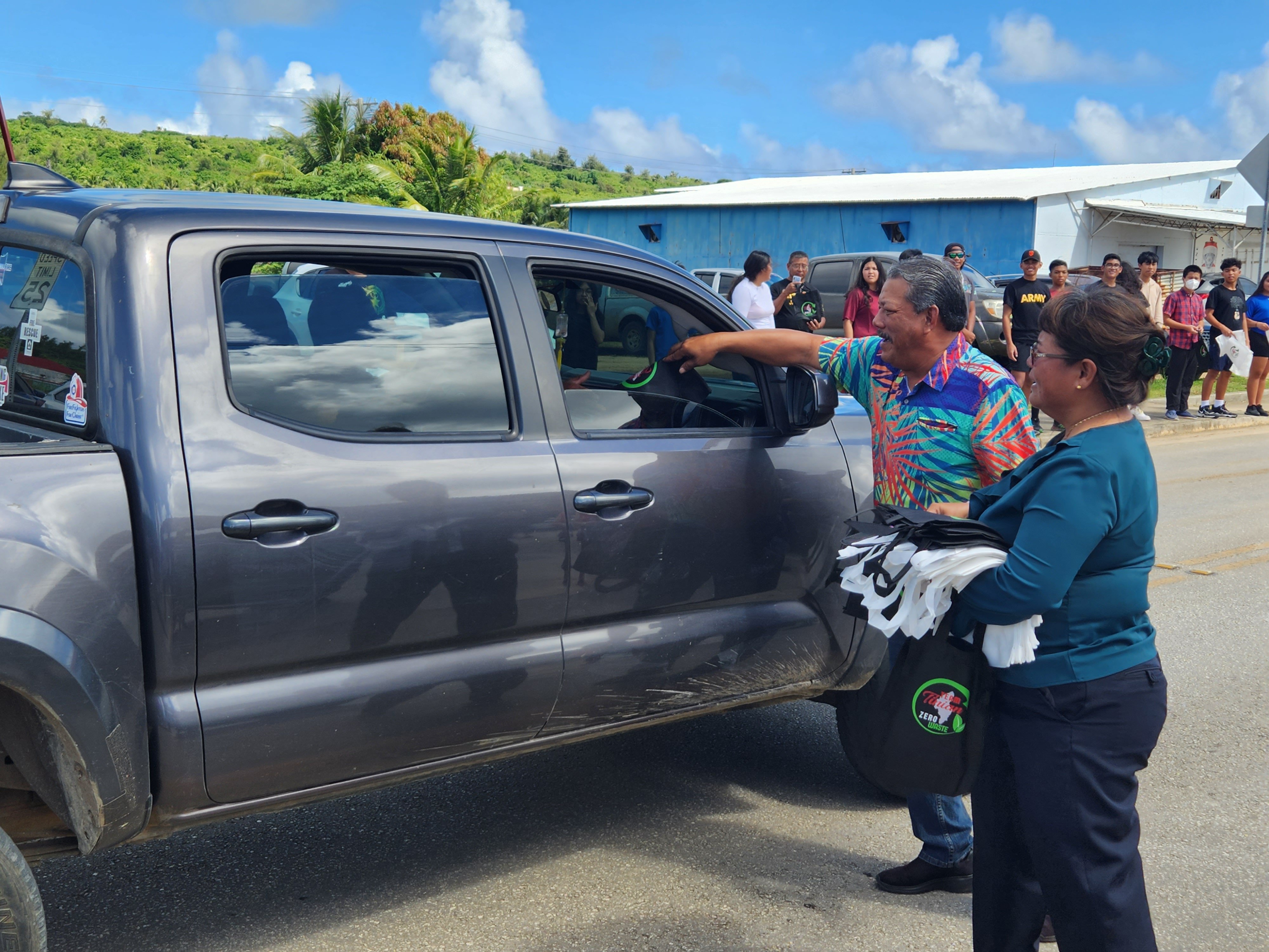 Mayor of Tinian and Aguiguan Edwin P. Aldan, 2nd right, hands over a reusable bag to a Tinian community member during a roadside waving held following a CNMI Recycles Week ceremony on Nov. 15 on Tinian.