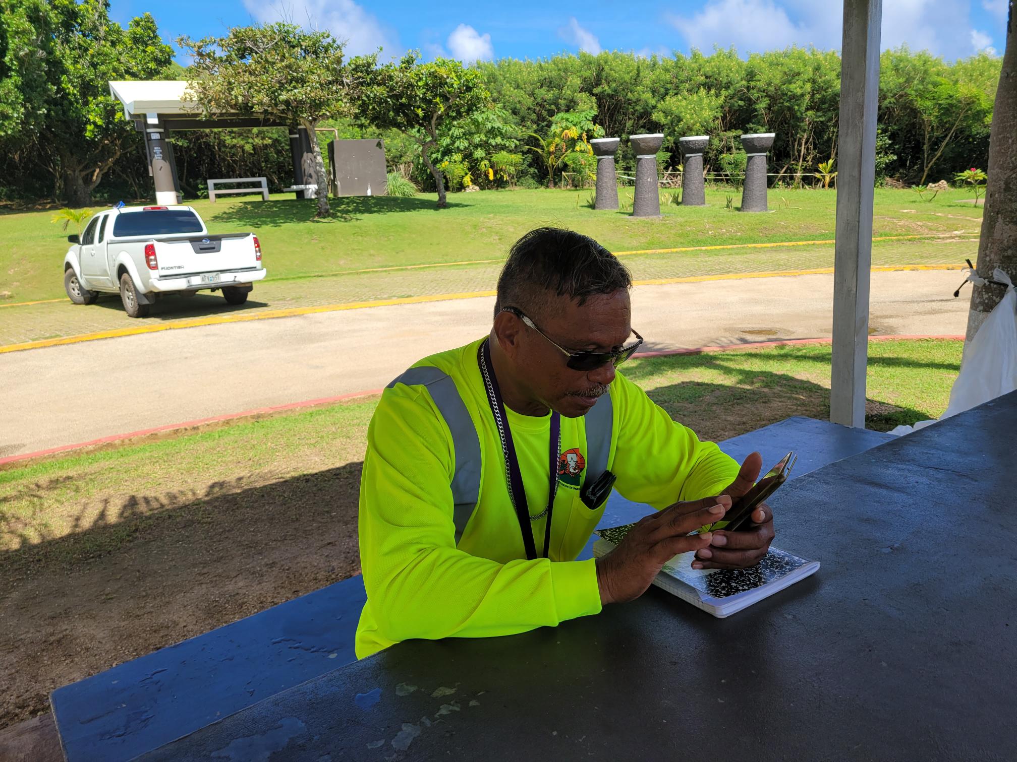 Max Aguon of the Division of Parks and Recreation checks his log sheet notes on his cell phone Friday at the Grotto.