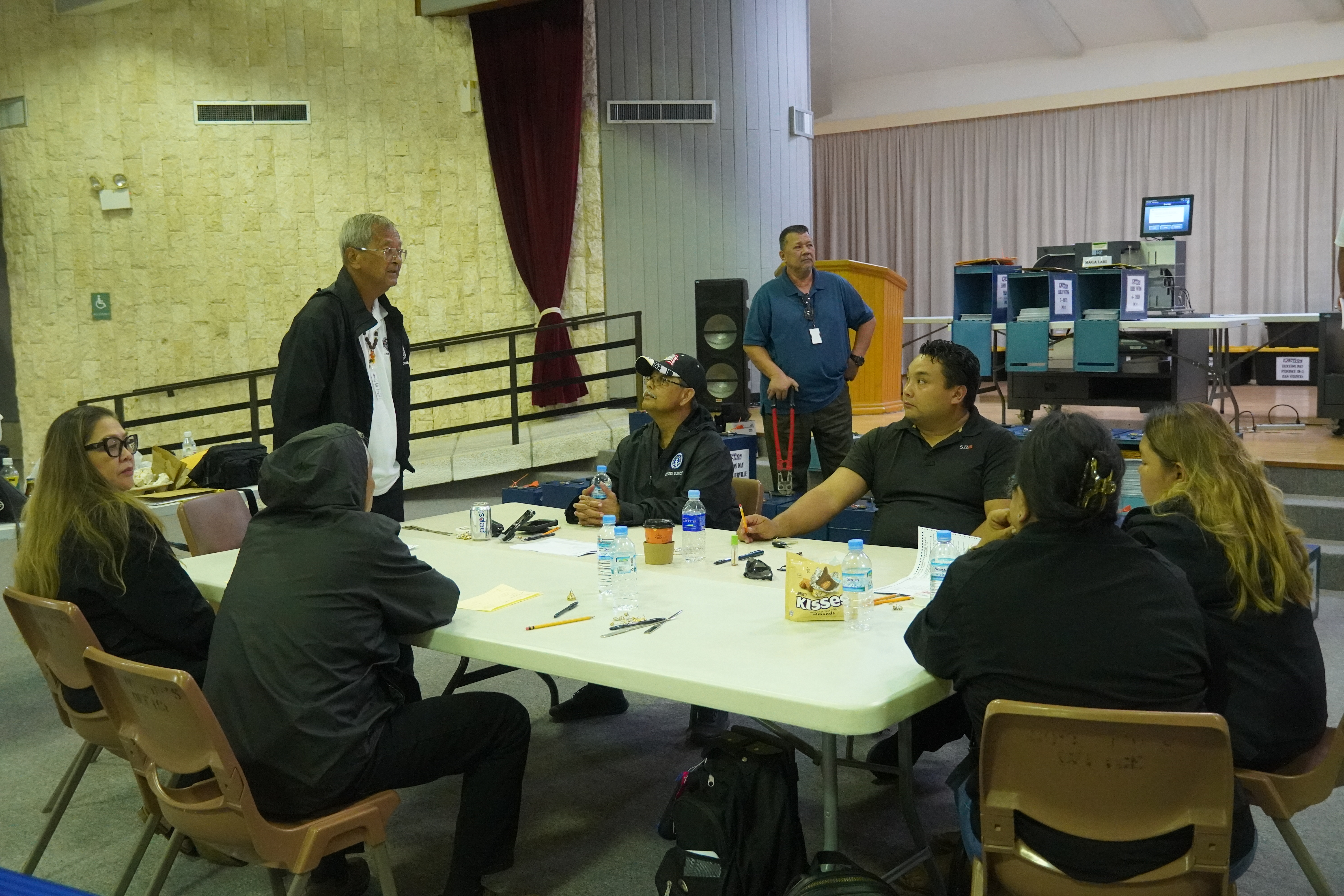 Commonwealth Election Commission Board Chair Jesus I. Sablan speaks to the other commissioners while Office of the Public Auditor investigator Edward Cabrera stands next to the ballot boxes with a heavy-duty metal cutter.