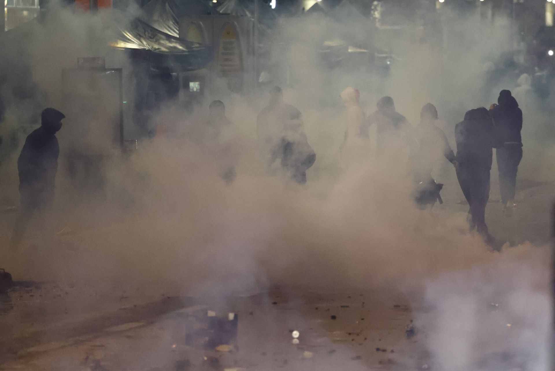 A group of people that the police are trying to disperse can be seen in the smoke during clashes after the World Cup match between Belgium and Morocco in Brussels, Belgium, Nov. 27, 2022.