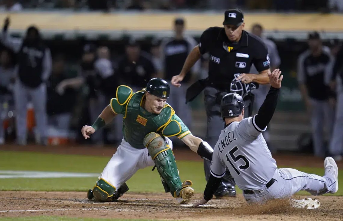 Oakland Athletics catcher Sean Murphy, left, tries to tag Chicago White Sox's Adam Engel (15), who scored the tying run during the ninth inning of a baseball game in Oakland, Calif., Sept. 9, 2022.