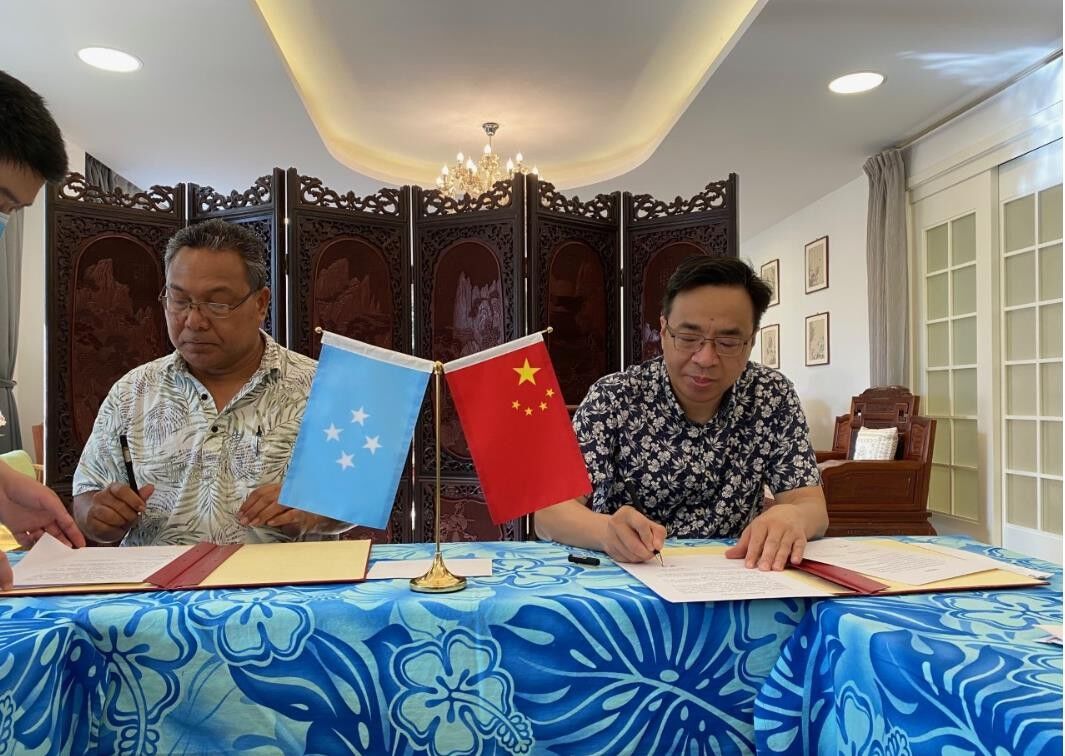 Alfred Ansin and Huang Zheng sign the relevant paperwork for the use of Chinese financial support for the construction of a gymnasium in Satawan.