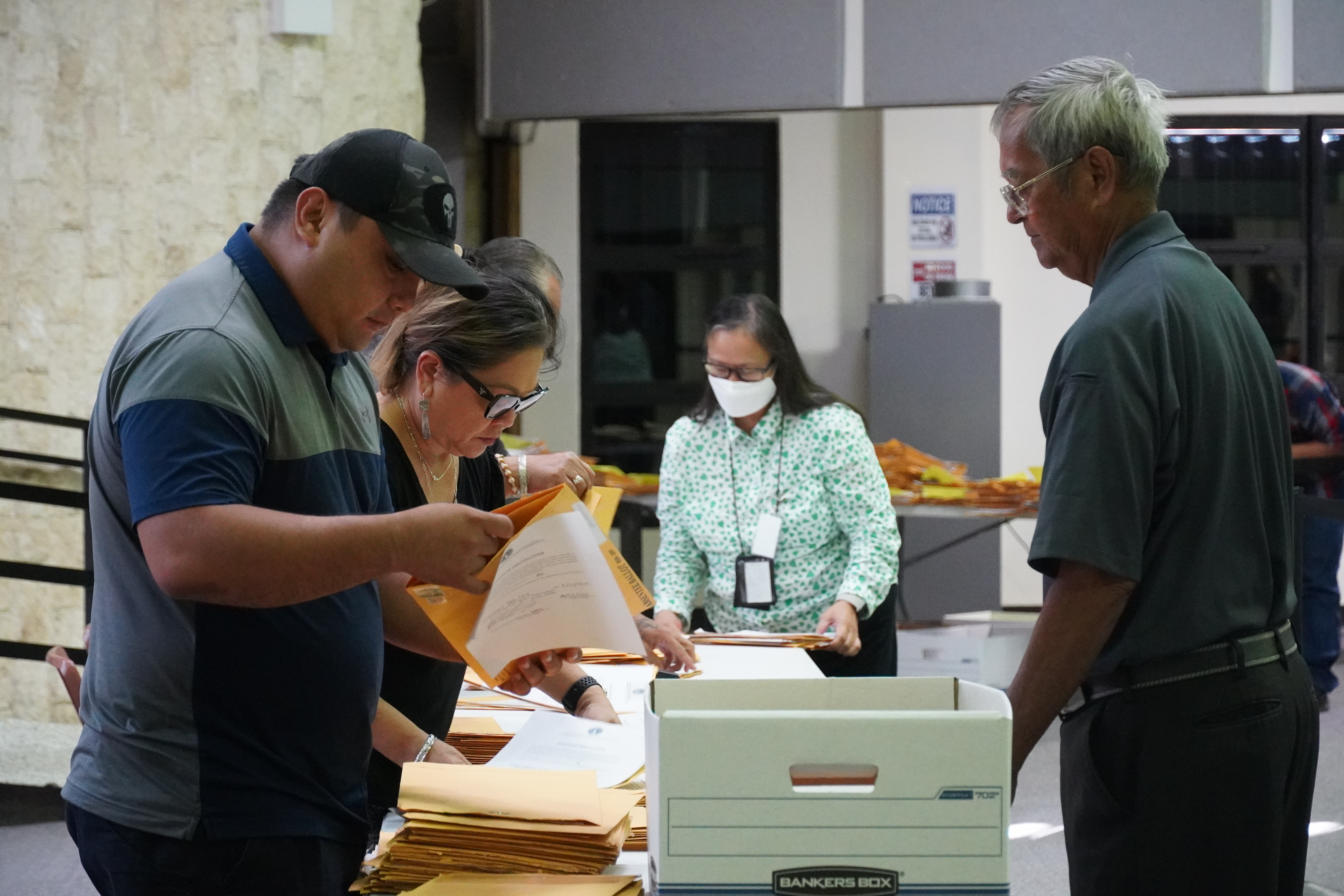 Election commissioners process absentee ballots with Deputy Attorney General Lillian A. Tenorio close by.