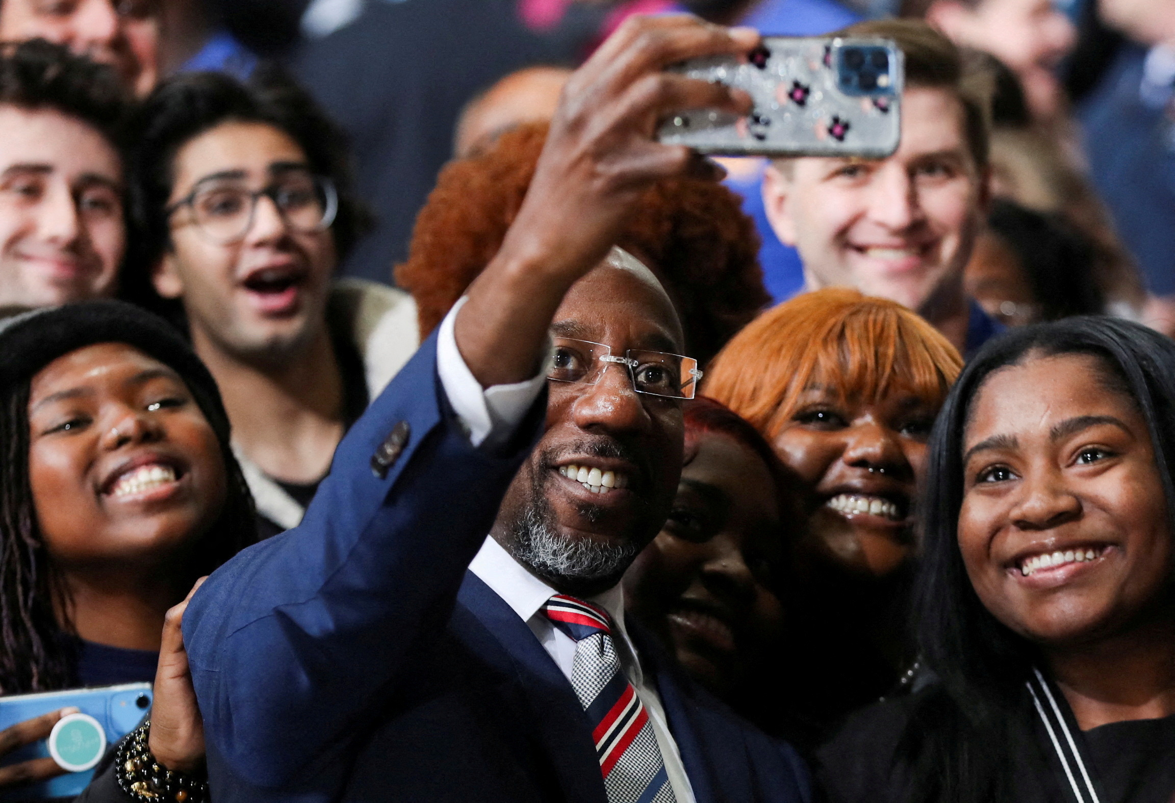 Democratic Senator Raphael Warnock takes a selfie with attendees as he campaigns ahead of the U.S. Senate runoff election in Atlanta, Georgia, Dec. 1, 2022.