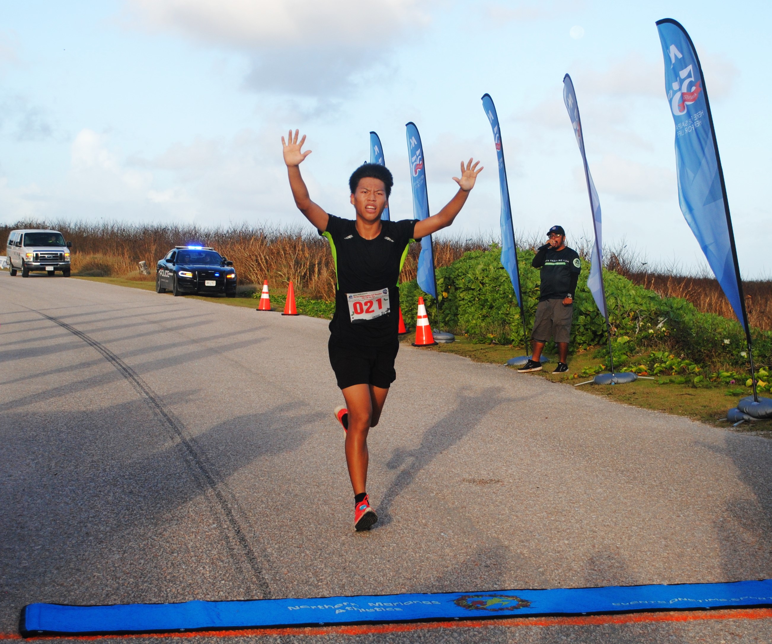 Samuel Zhu raises his arms as he crosses the finish line of the inaugural Run Saipan Holiday Half Marathon on Saturday at Banzai Cliff.
