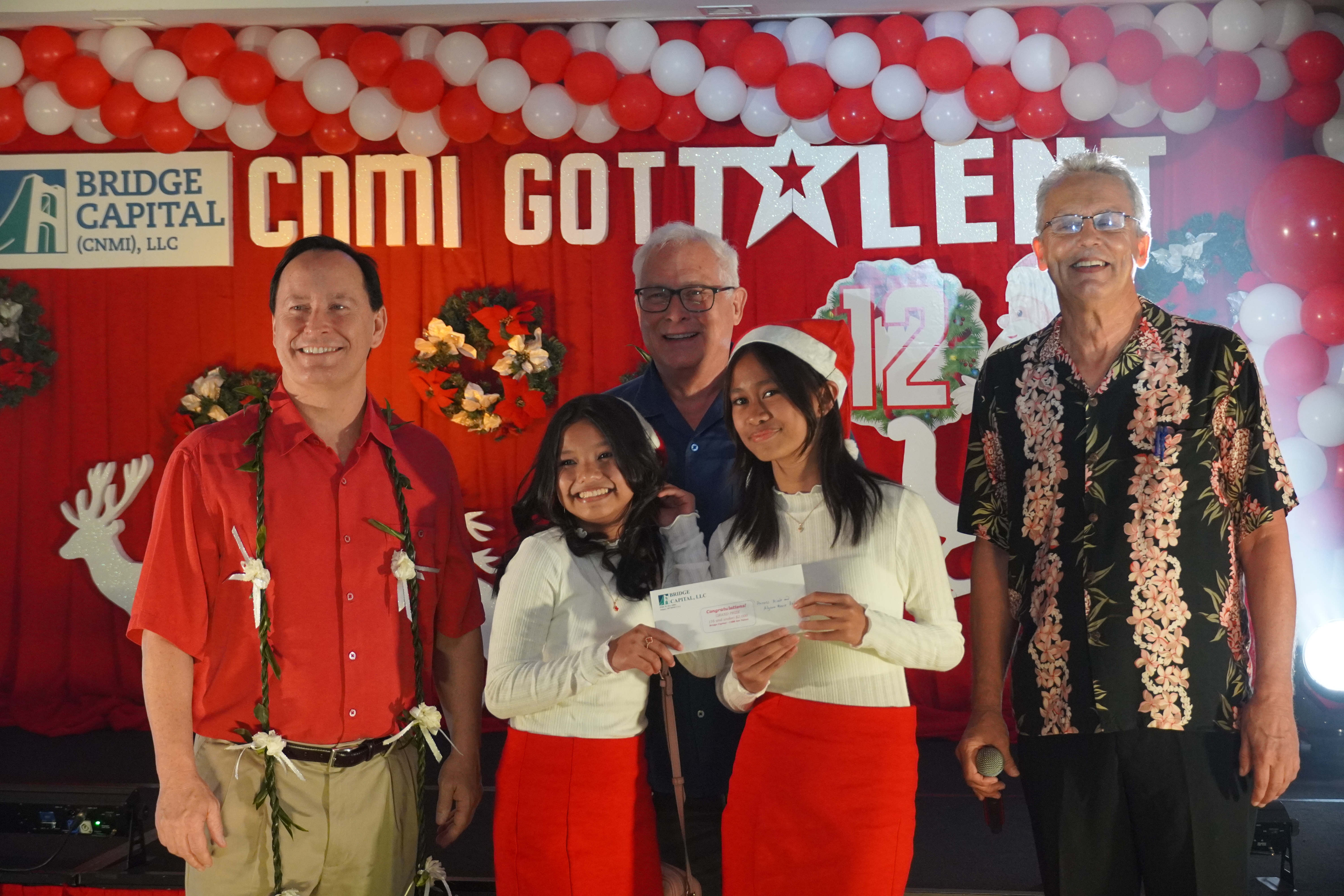 Princess Nicole Rigua and Alyana Marie Rotap — eight-graders at Hopwood Middle School  are the 2022 CNMI Got Talent champions in the kids category. They are pictured here with Bridge Capital LLC co-owners John Baldwin and Shawn Scott, and the event's master of ceremony, Brad Cleven.