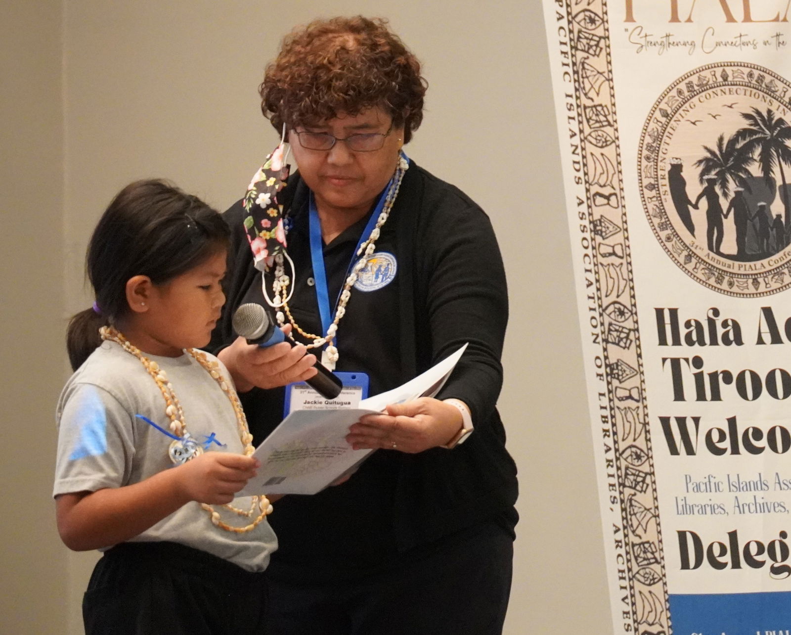 Young Chamorro author Jacqueline Iris Quitugua reads her book, "Si Tatå-hu (My Dad)," to the PIALA Conference delegates and guests, as her grandmother, Jacqueline A. Quitugua, M.Ed., a senior director of the CNMI Public School System, assists her.