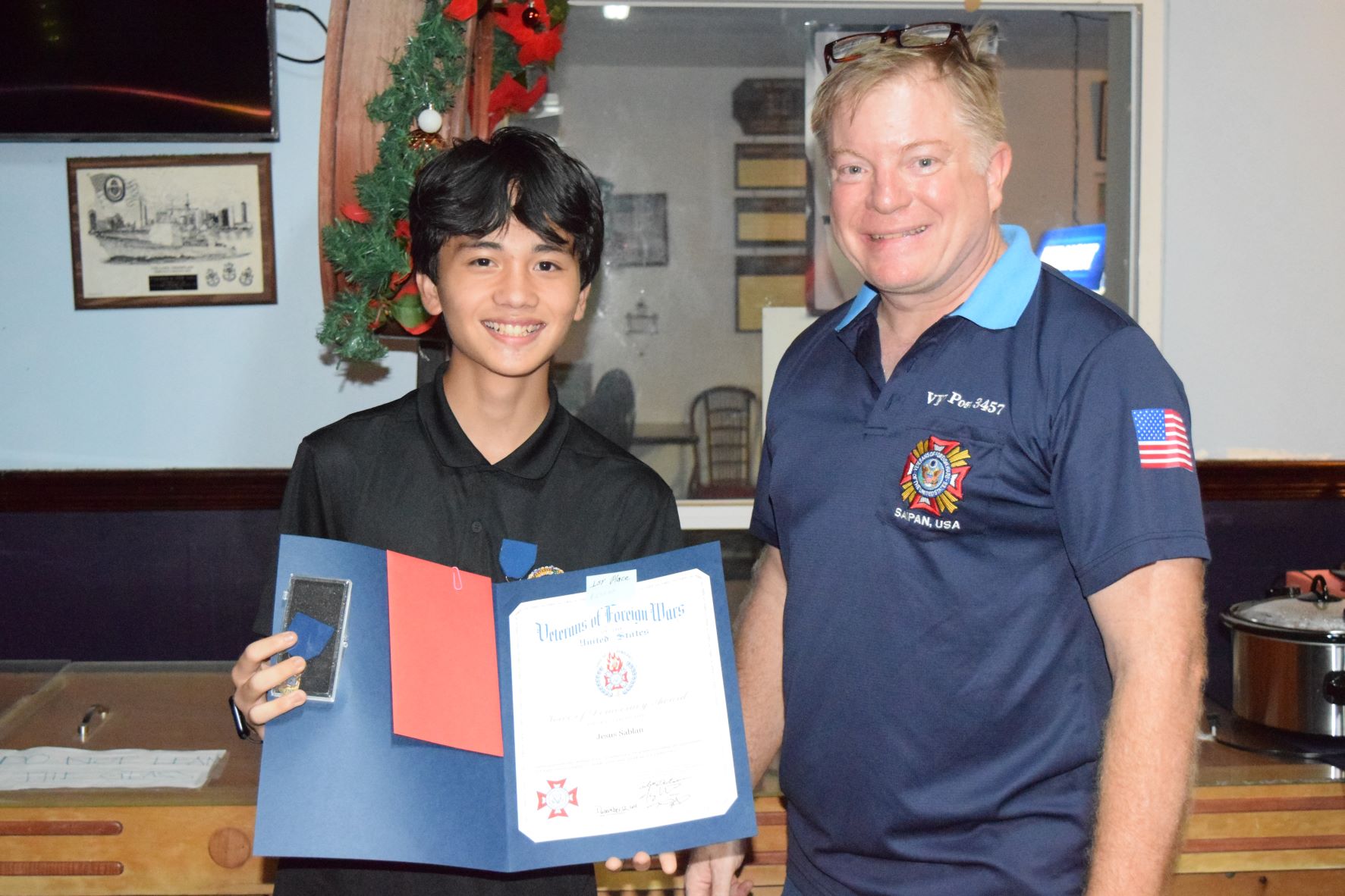 Veterans of Foreign Wars Voice of Democracy essay competition first place winner, Jesus T. Sablan, holds his awards as he poses for a photo with VFW Post 347 Commander Robert DeRocher at the VFW Post 3457 headquarters in Garapan on Monday.