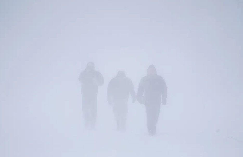 Three men walk down Richmond Avenue in whiteout conditions during a sustained blizzard in Buffalo, N.Y. on Saturday, Dec. 24, 2022.