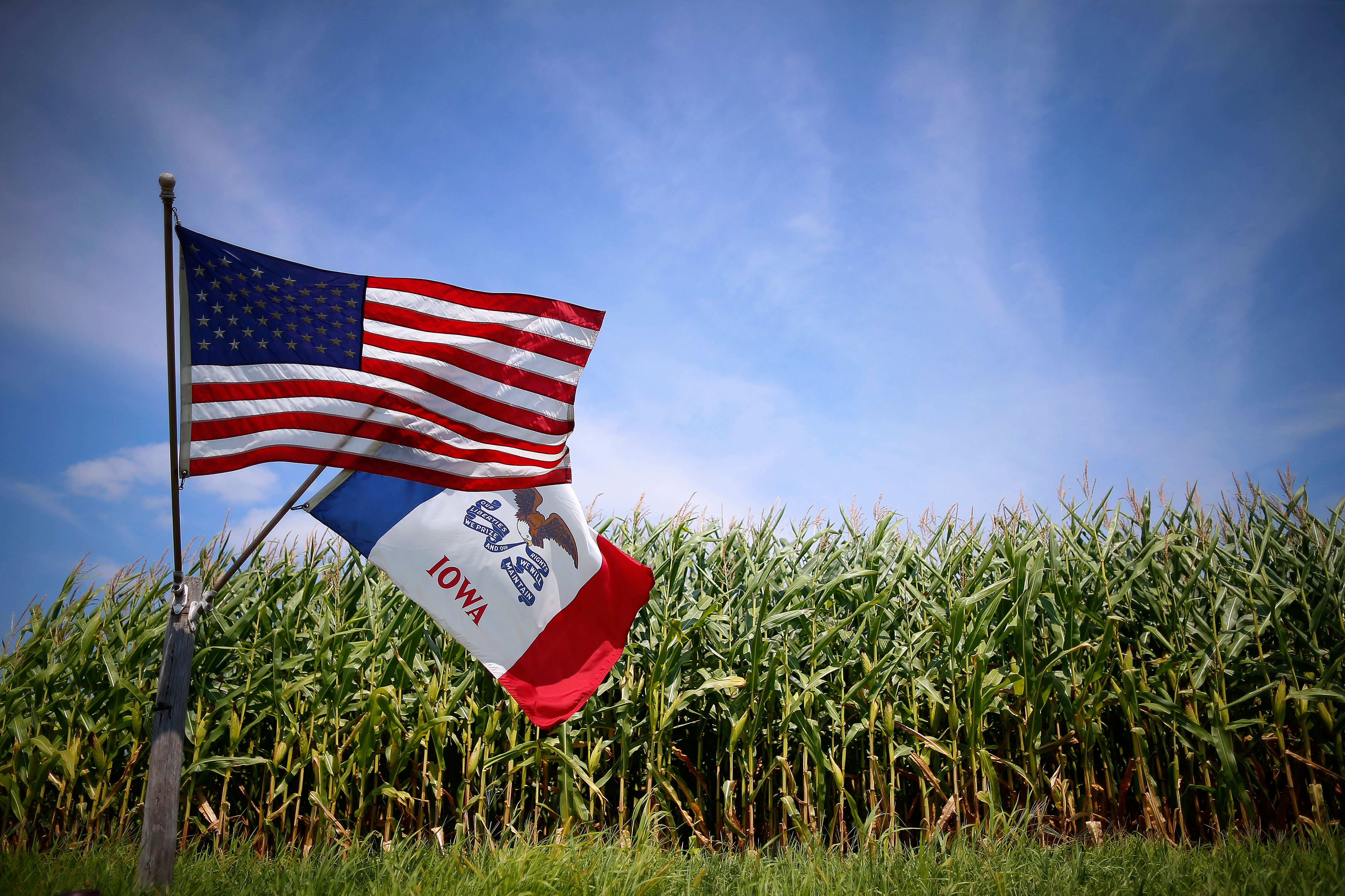 A U.S. and Iowa state flags are seen next to a corn field in Grand Mound, Iowa on Aug. 16, 2015.