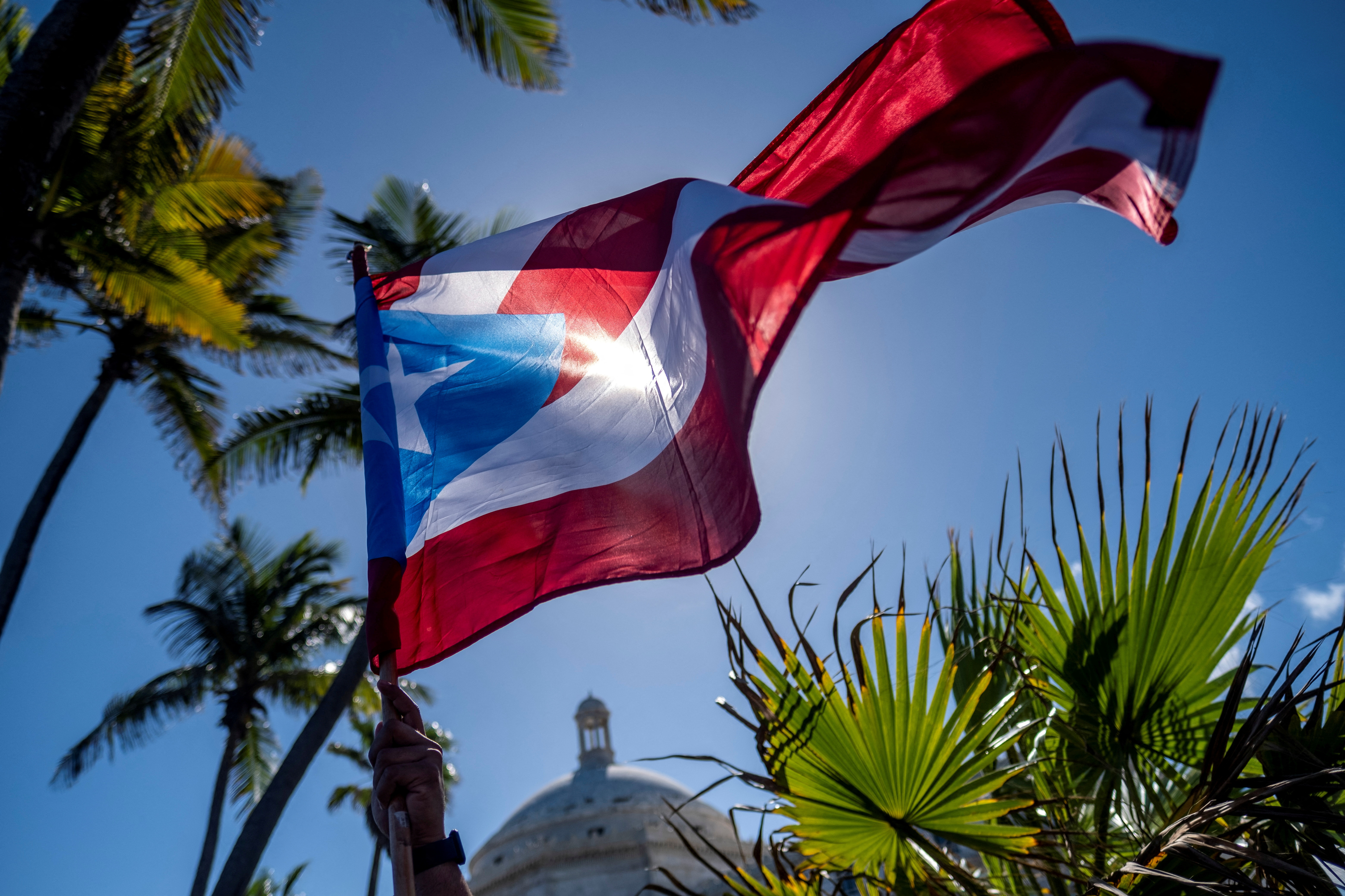 A person holds a Puerto Rican flag in front of the Capitol during a protest of teachers demanding salary increase and better working conditions, in San Juan, Puerto Rico on Feb. 9, 2022.