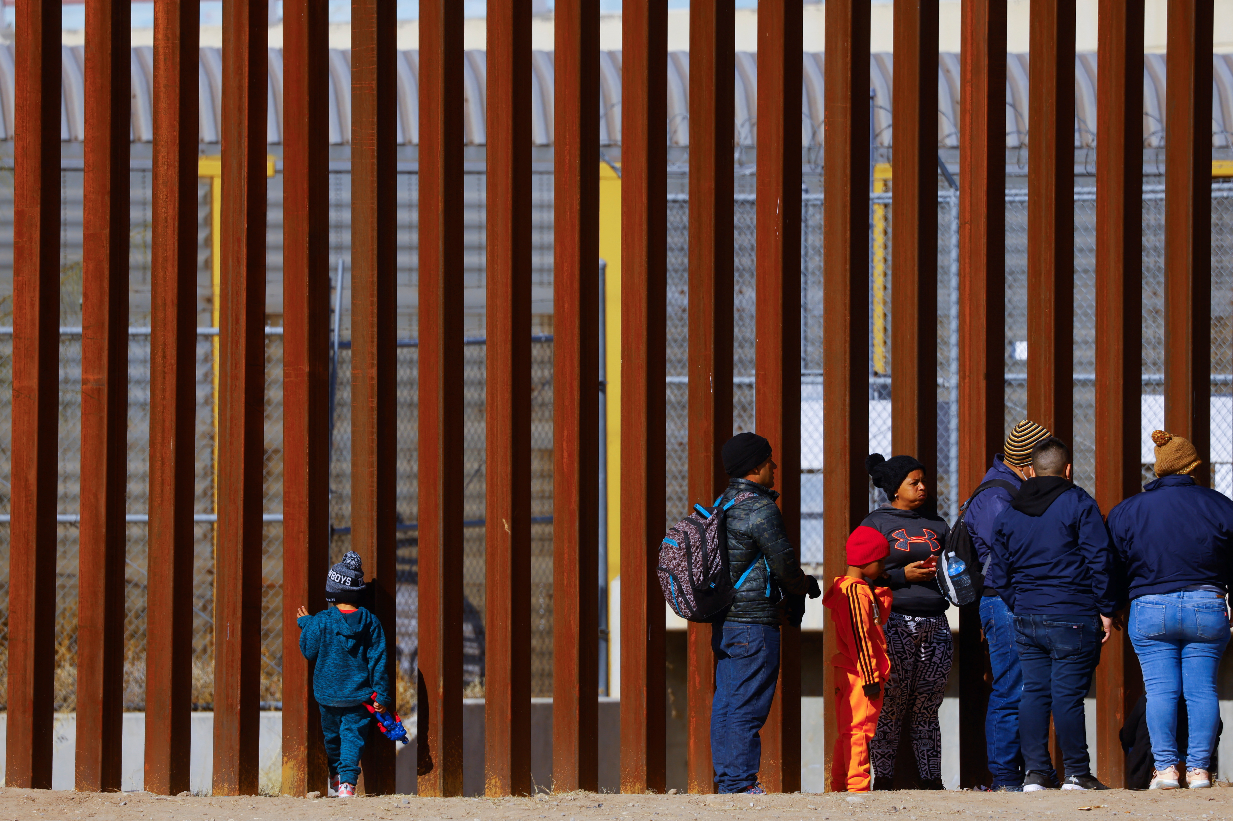 George, 5, a migrant boy from Venezuela traveling with his family, looks through the border wall as they queue to request asylum in El Paso, Texas, seen from Ciudad Juarez, Mexico, Dec. 27, 2022.
